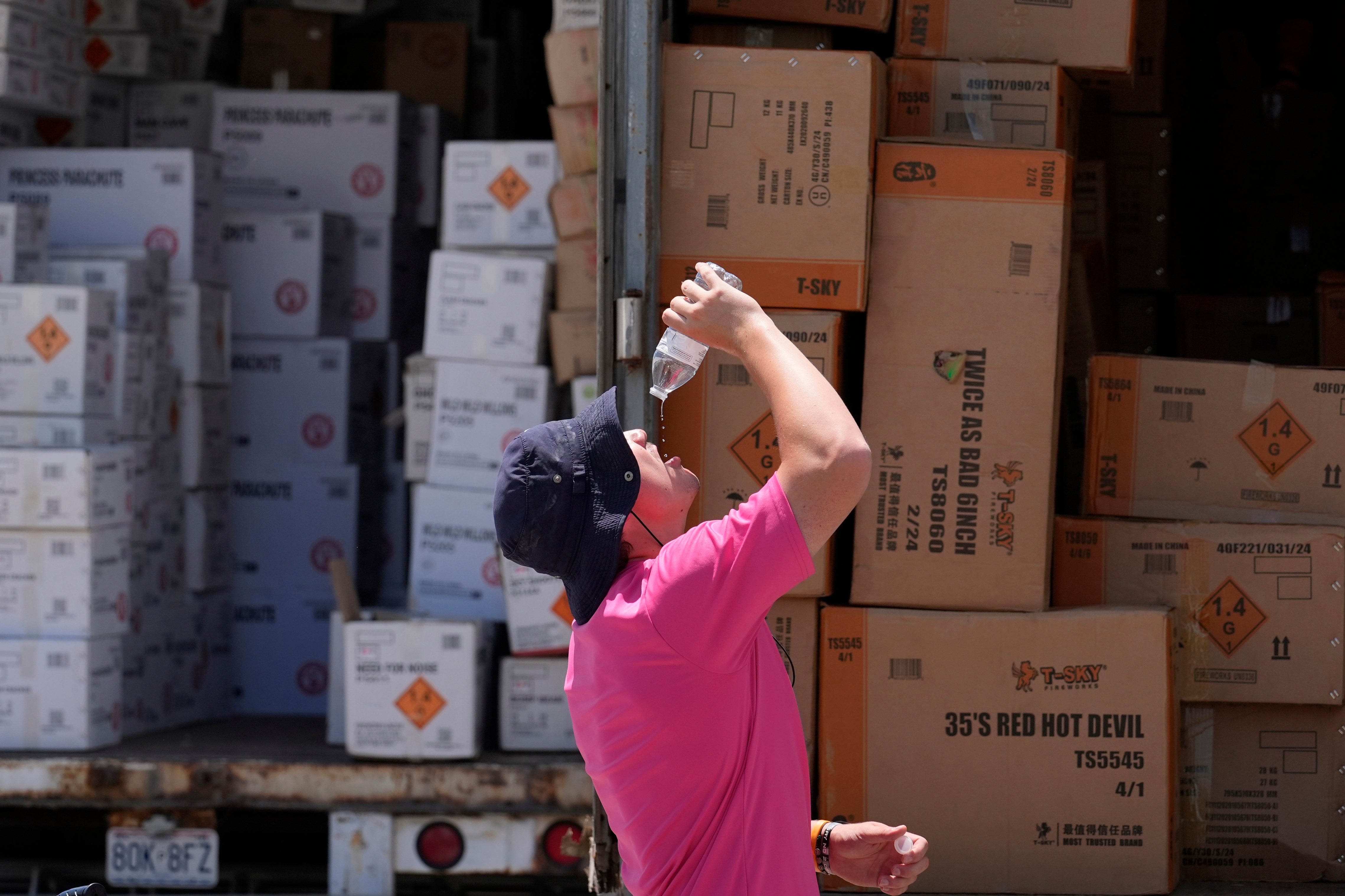 Wyatt Seymore pours the last drops of liquid from a water bottle into his mouth as he takes a break from unloading a stiflingly hot trailer of fireworks outside Powder Monkey Fireworks ahead of the opening of the stand, June 17, 2024, in Weldon Spring, Mo. (AP Photo/Jeff Roberson, File)