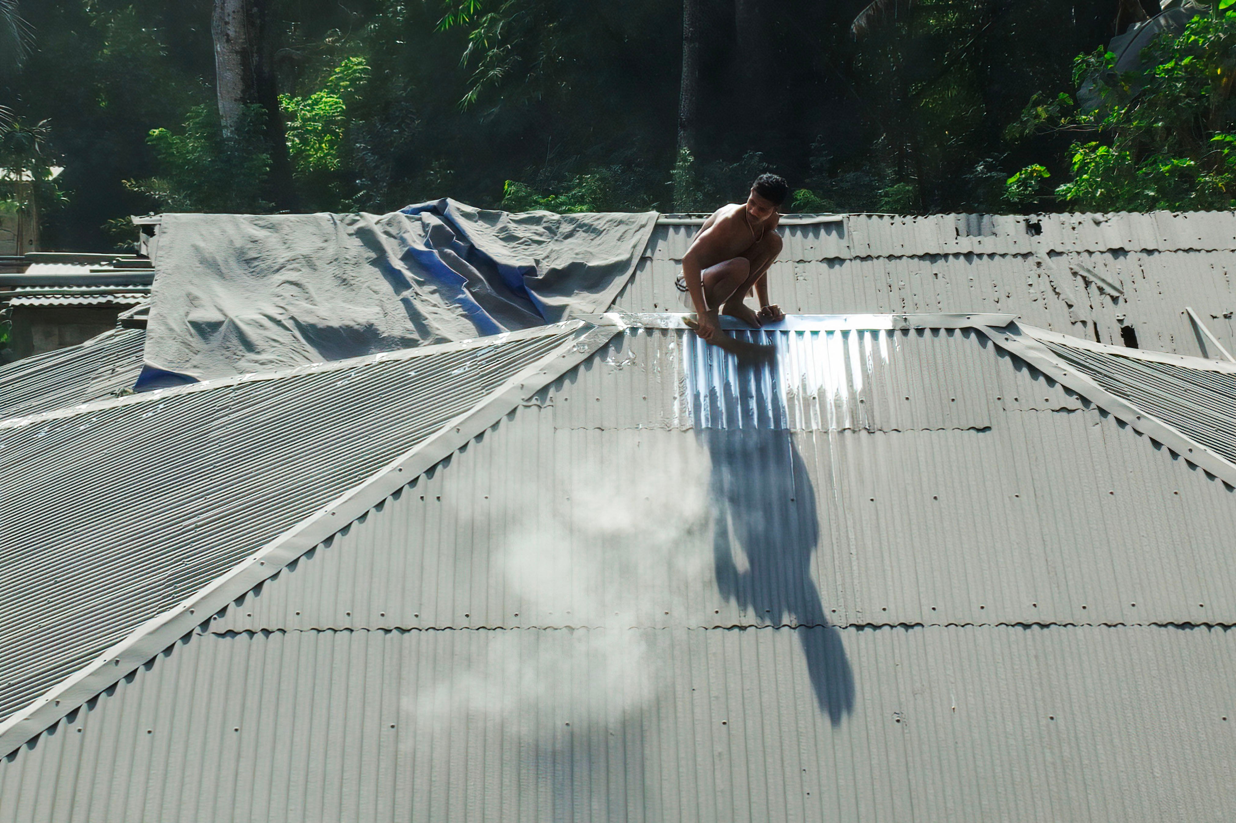 A villager cleans the roof of his home from volcanic ash a day after Mount Lewotobi Laki-Laki spewed ashes