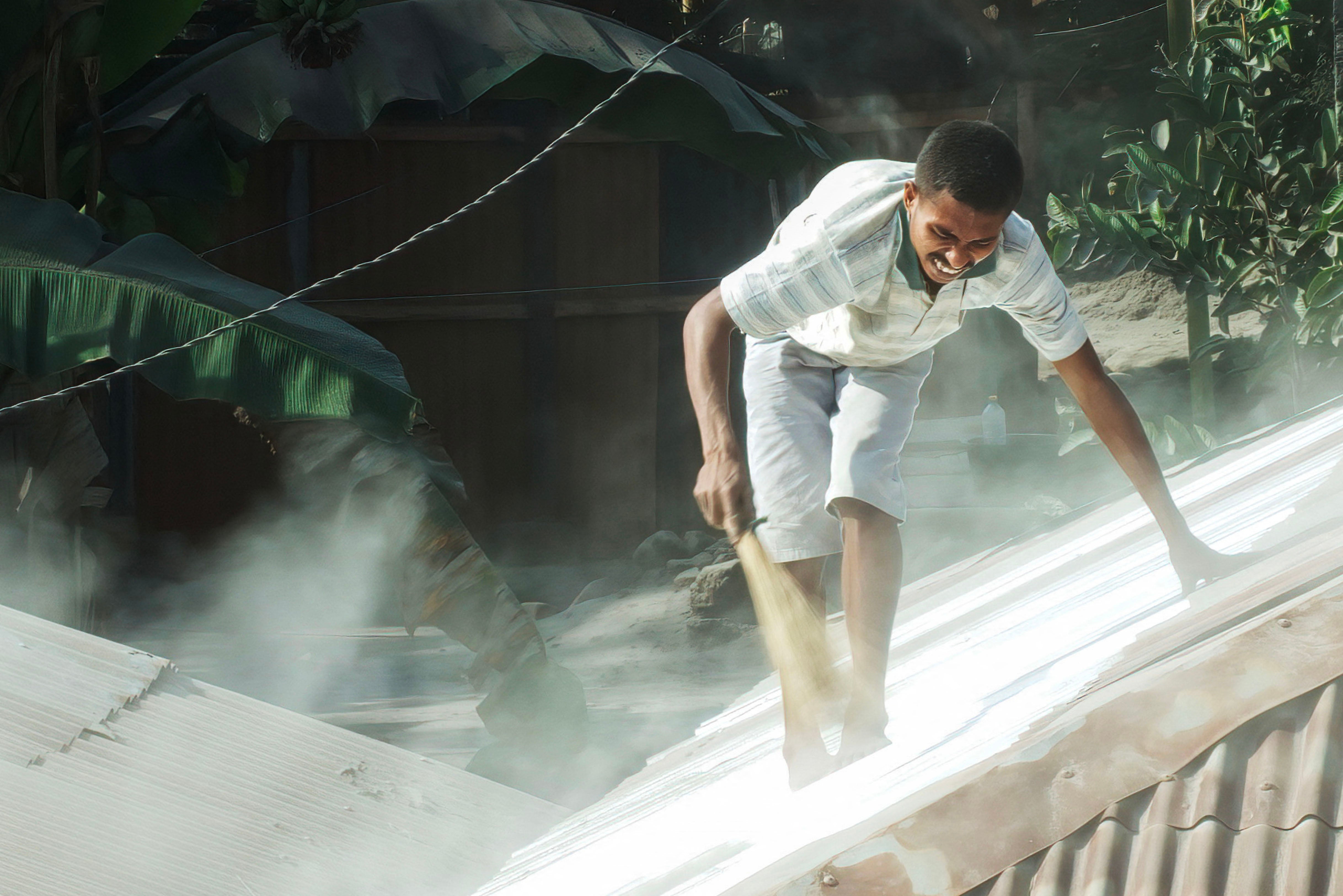 A villager cleans the roof of his home from volcanic ash a day after Mount Lewotobi Laki-Laki spewed ashes more than 10 kilometers into the air in Sikka