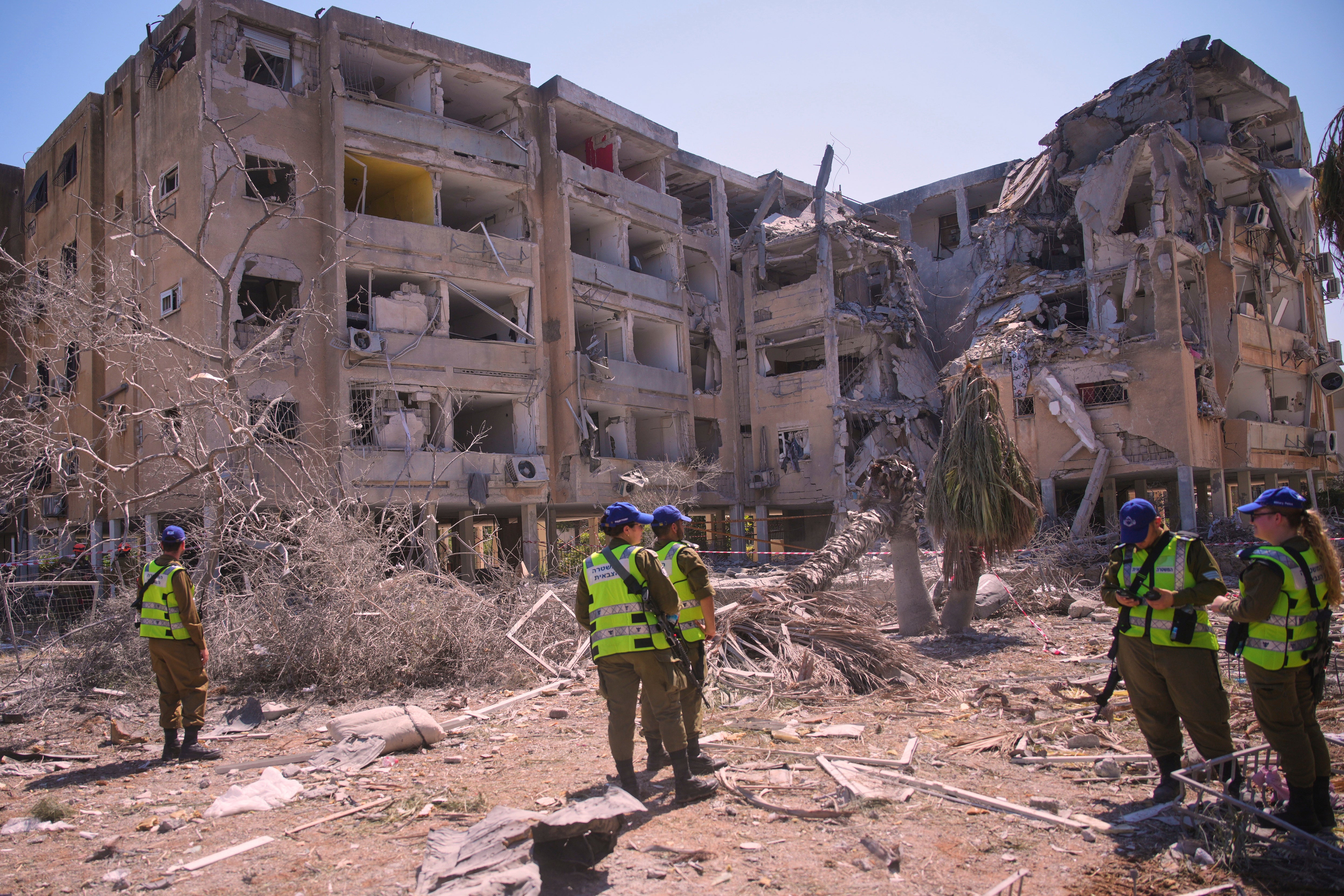 Israeli security forces stand next to a destroyed building that was hit by a missile fired from Iran, in Holon, near Tel Aviv