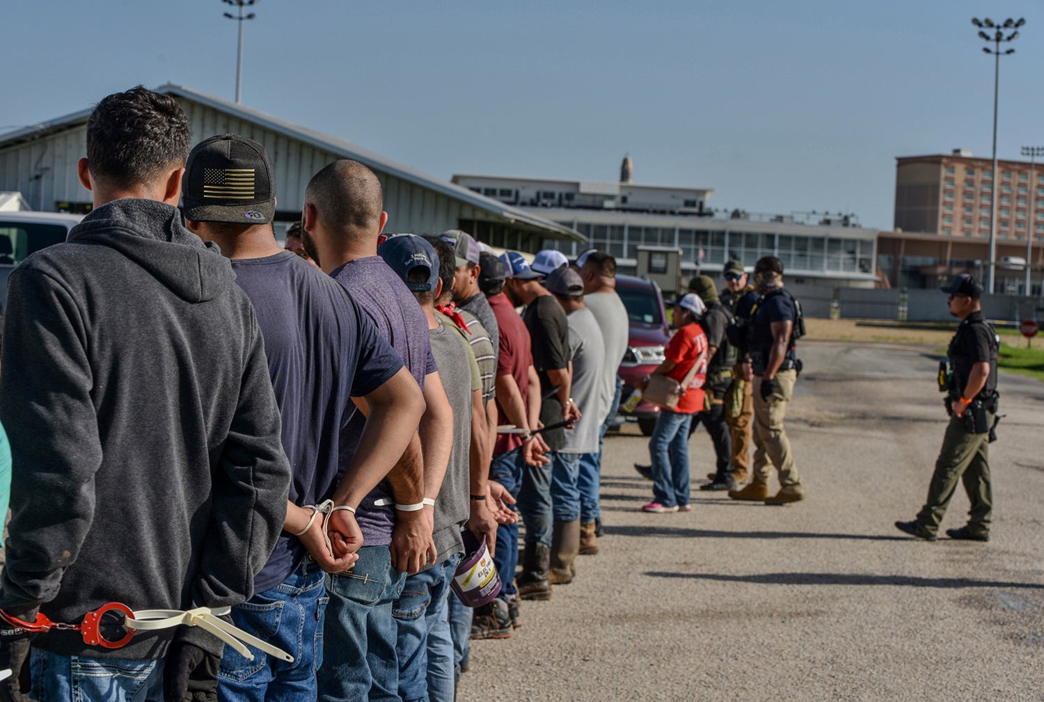 Workers stand handcuffed after being arrested by ICE agents at Delta Downs Racetrack, Hotel and Casino in Calcasieu Parish, near Vinton, Louisiana, on June 18, 2025