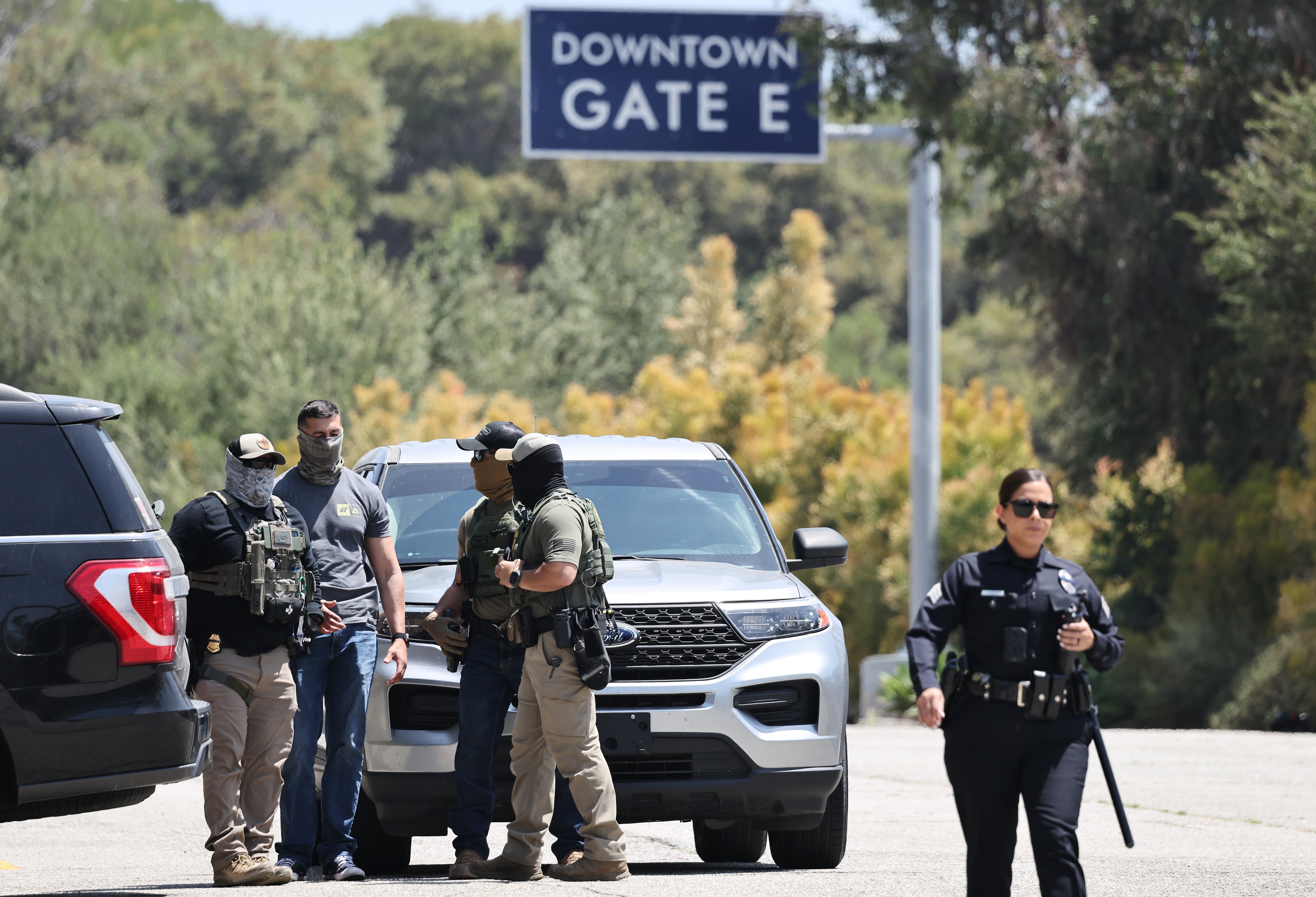 An LAPD officer walks past masked federal agents Dodger Stadium