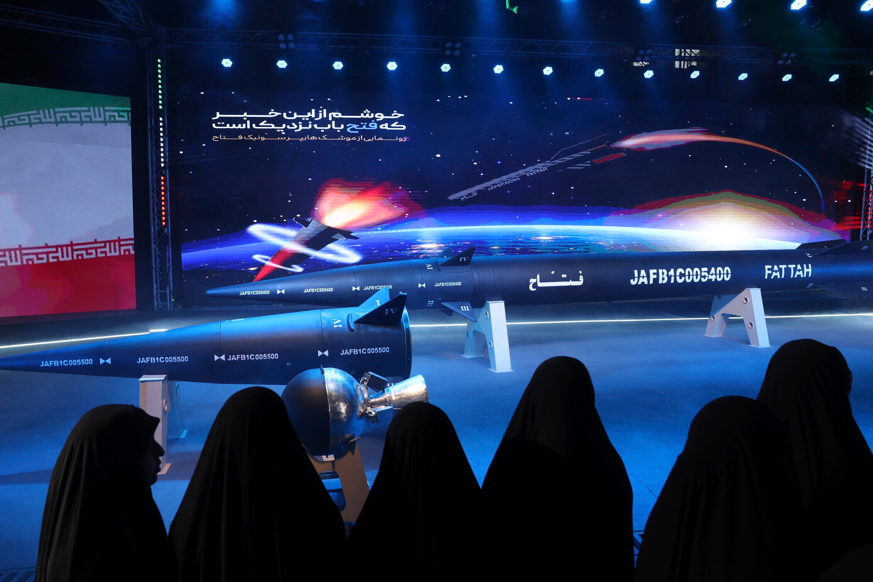 Women look at a Fattah missile in a ceremony in Tehran, Iran