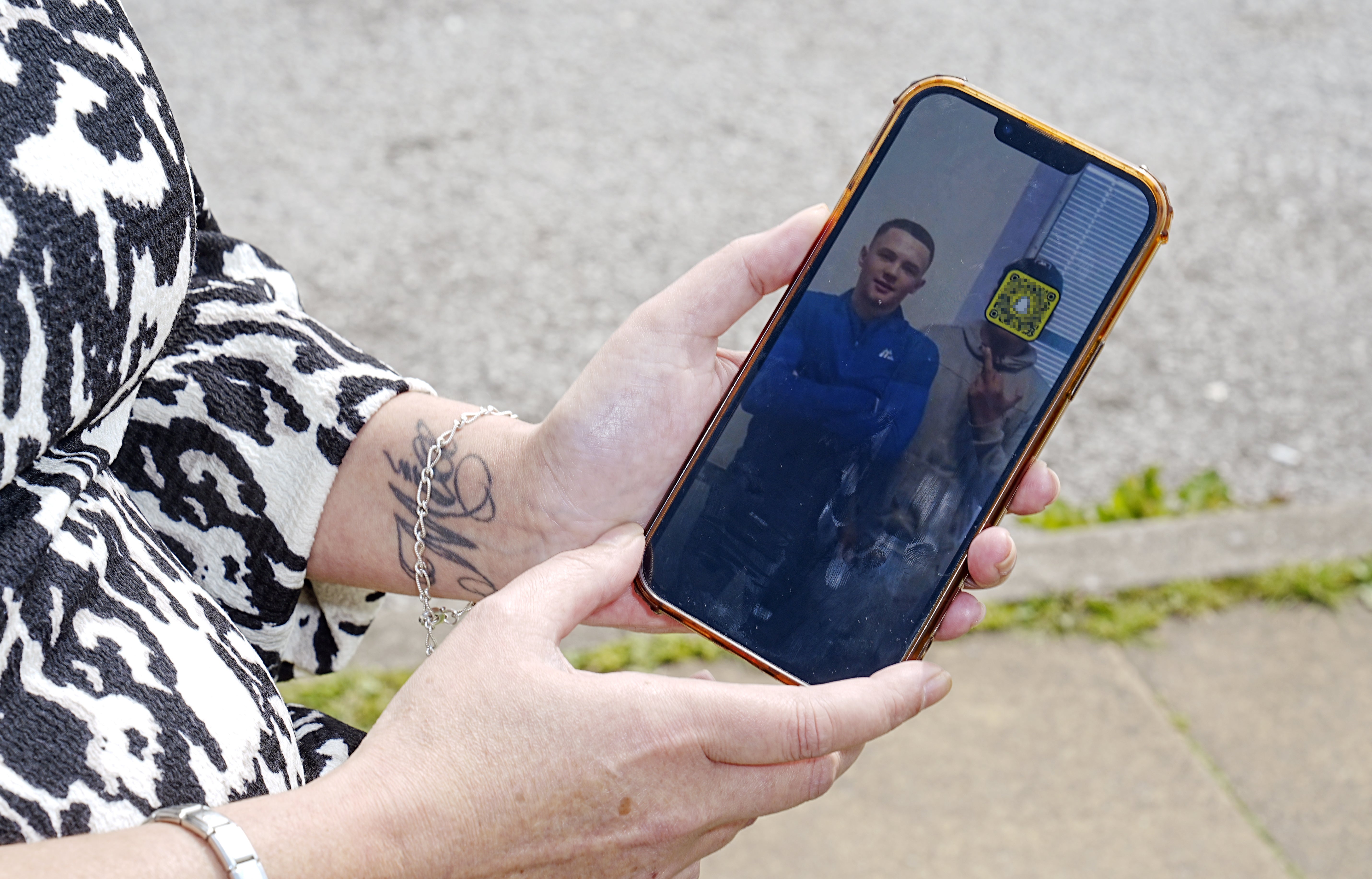 Leeann White looks on her mobile phone at a picture on the social media app Snapchat – which appears to show Harry Gilbertson