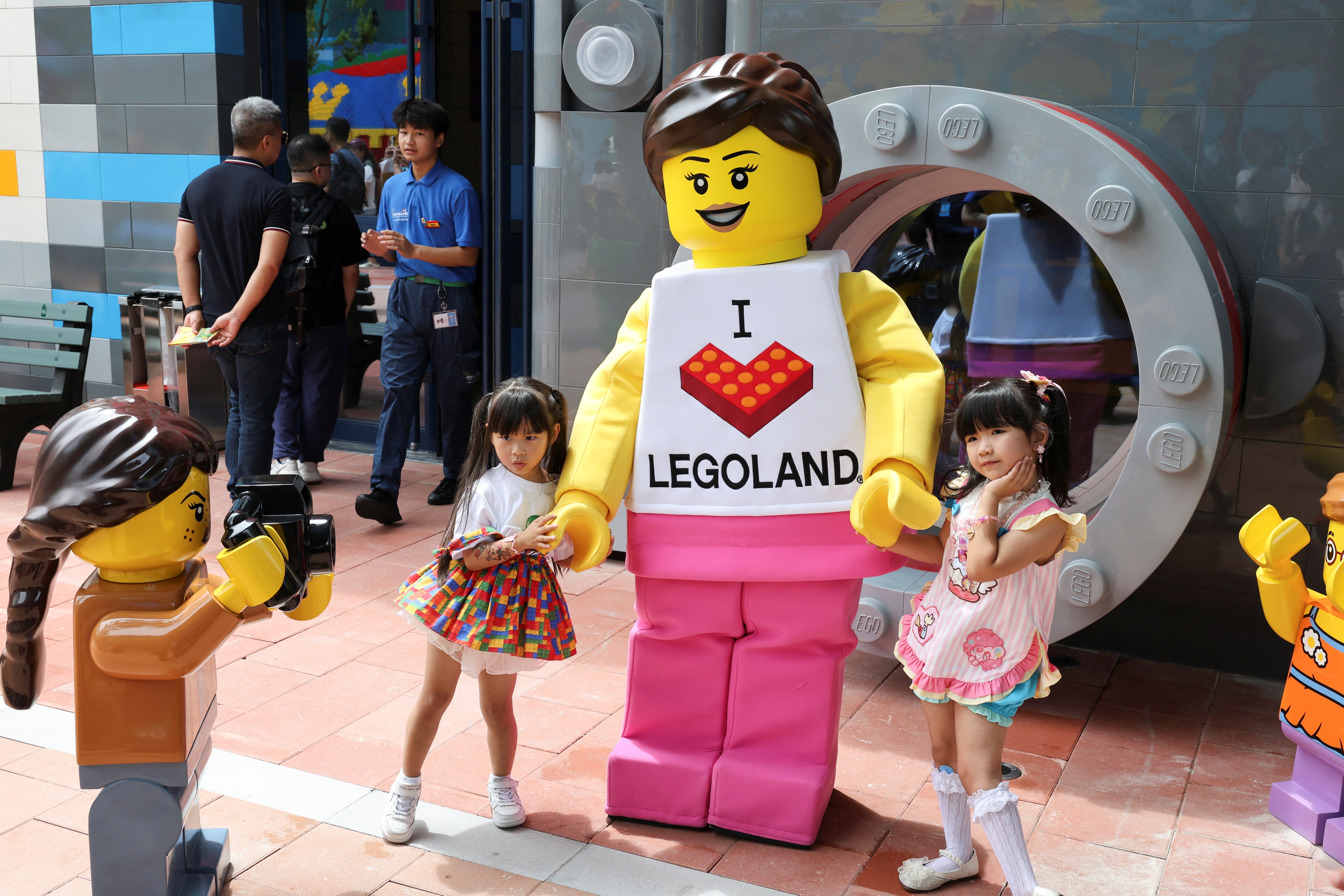 Children pose for a photo with a mascot as they visit Legoland Shanghai Resort