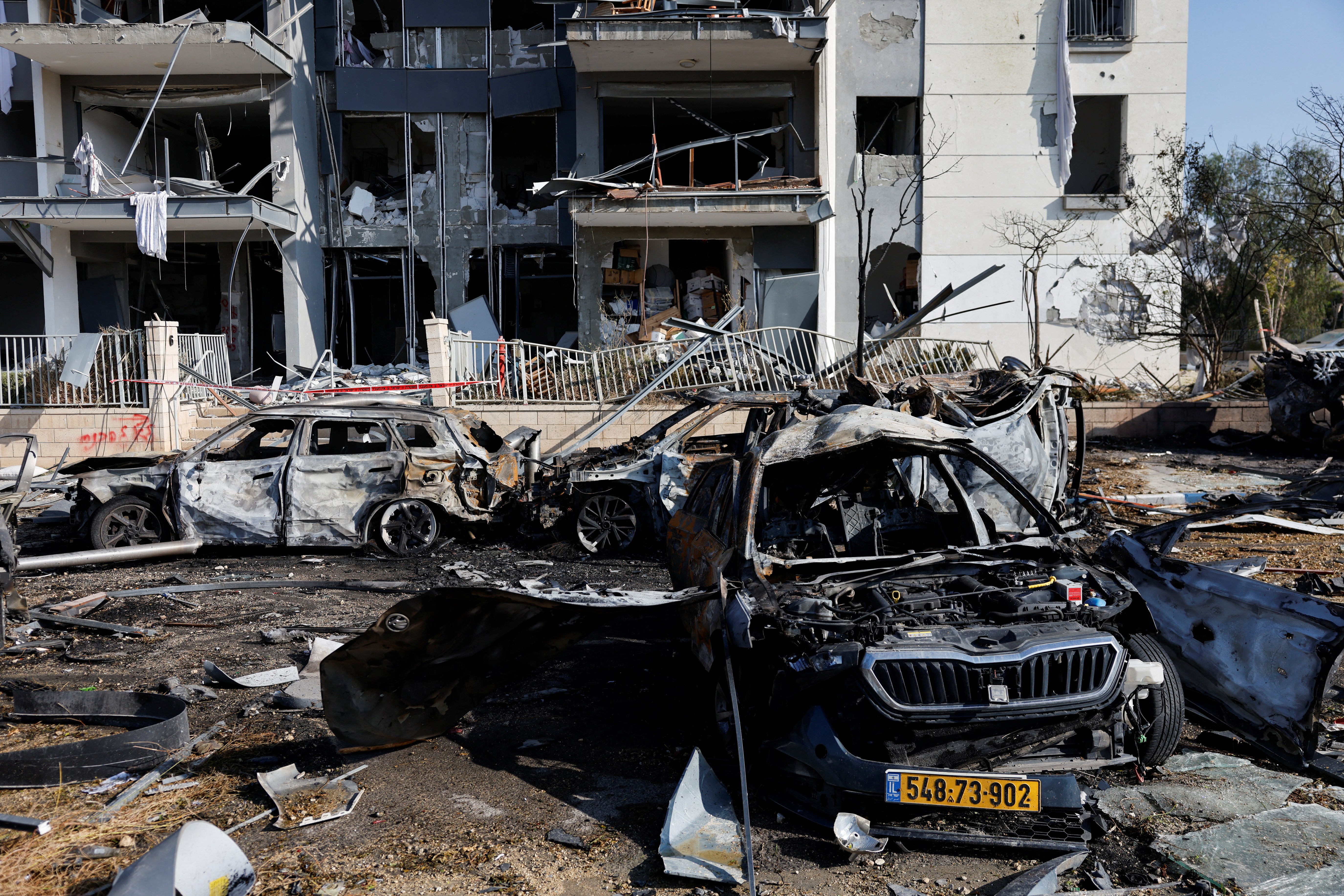 A view of burnt cars and a damaged building at an impact site following Iran's missile strike on Israel, in Be'er Sheva, Israel