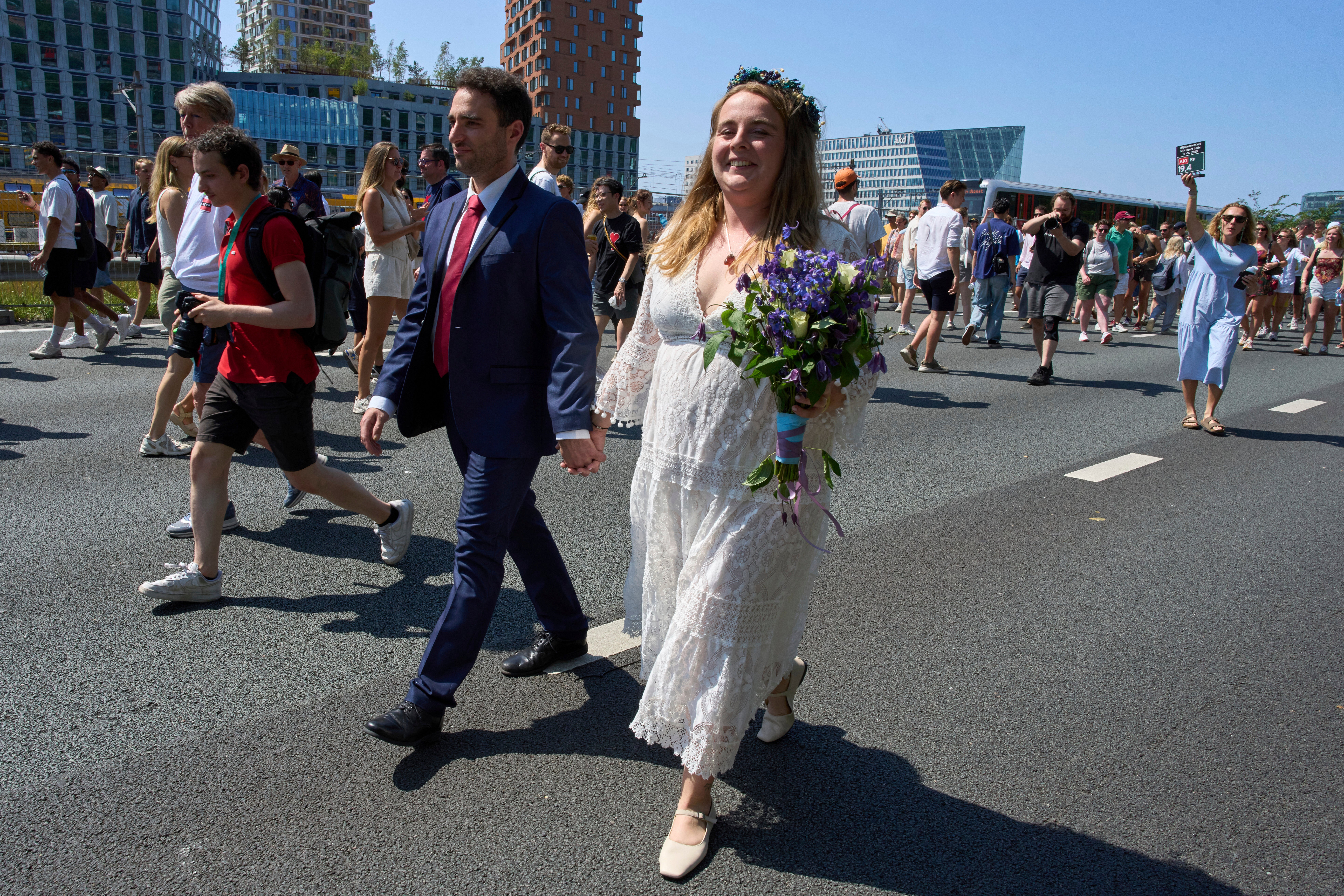 Zuzana Lisowska and Yuri Iozzelli celebrate after getting married on a highway bypass, as the Dutch capital celebrates its 750th anniversary with weddings, music and other events on the A10 ring road in Amsterdam, Netherlands, Saturday, June 21, 2025. (AP Photo/Peter Dejong)