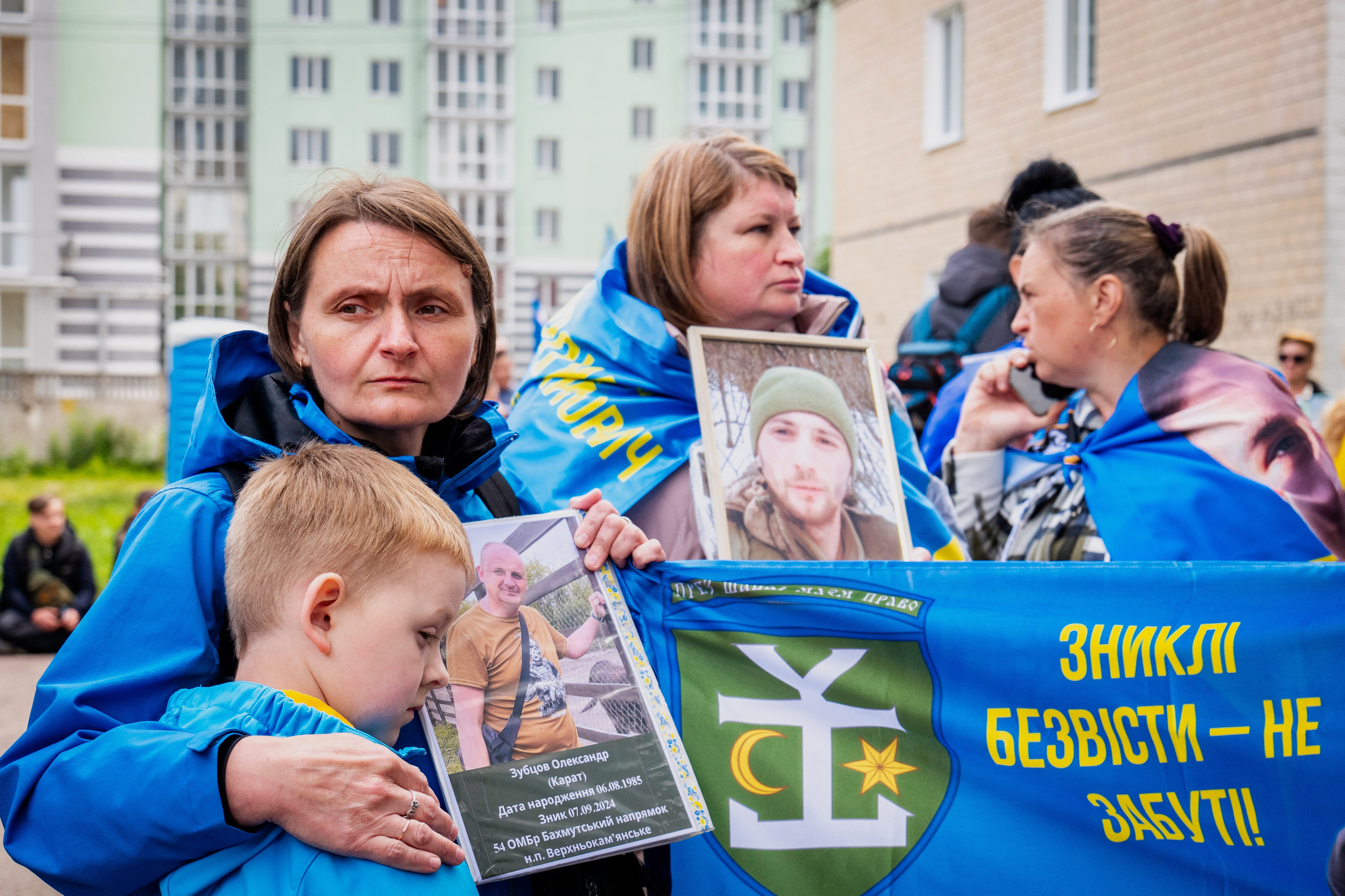 Ukrainians hold photos of their missing relatives during as they watch freed Ukrainian soldiers arrive after a POW exchange with Russia in the Chernyhiv region of Ukraine, Friday, June 20, 2025. (AP Photo/Dan Bashakov)