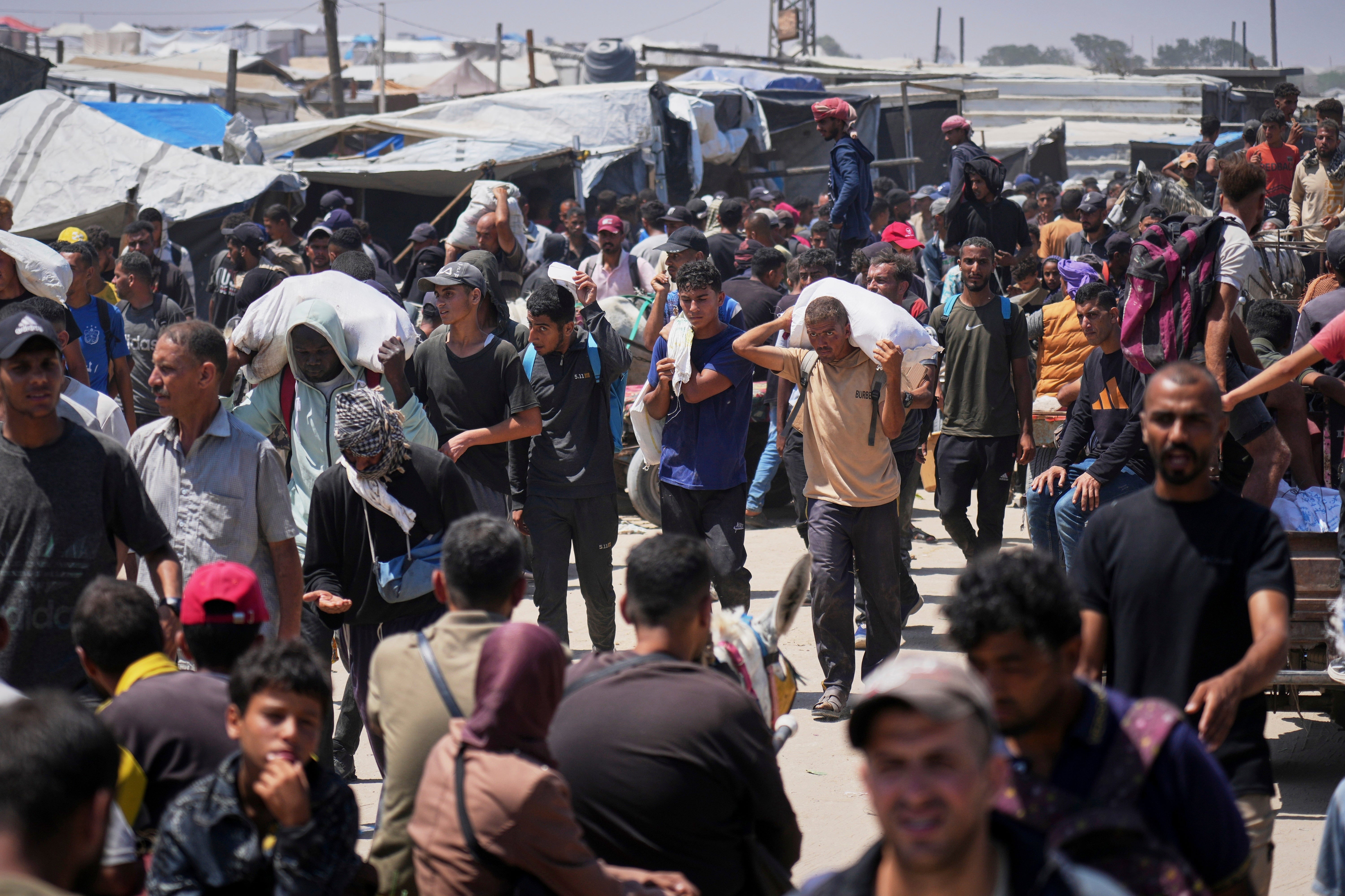 Palestinians carry bags and boxes of food near a Gaza Humanitarian Foundation aid site