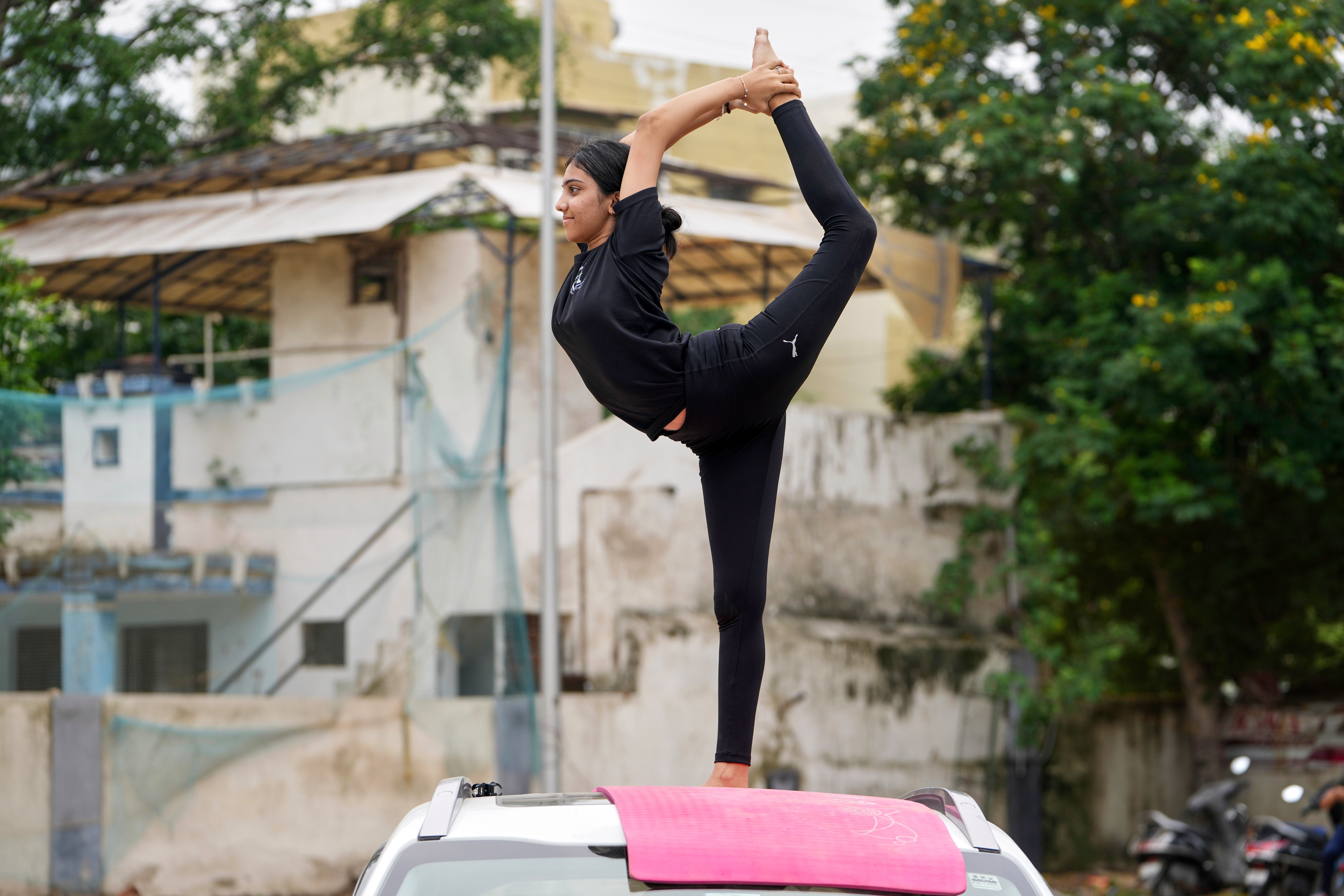 A girl performs yoga on top of a parked car to celebrate International Day of Yoga in Ahmedabad