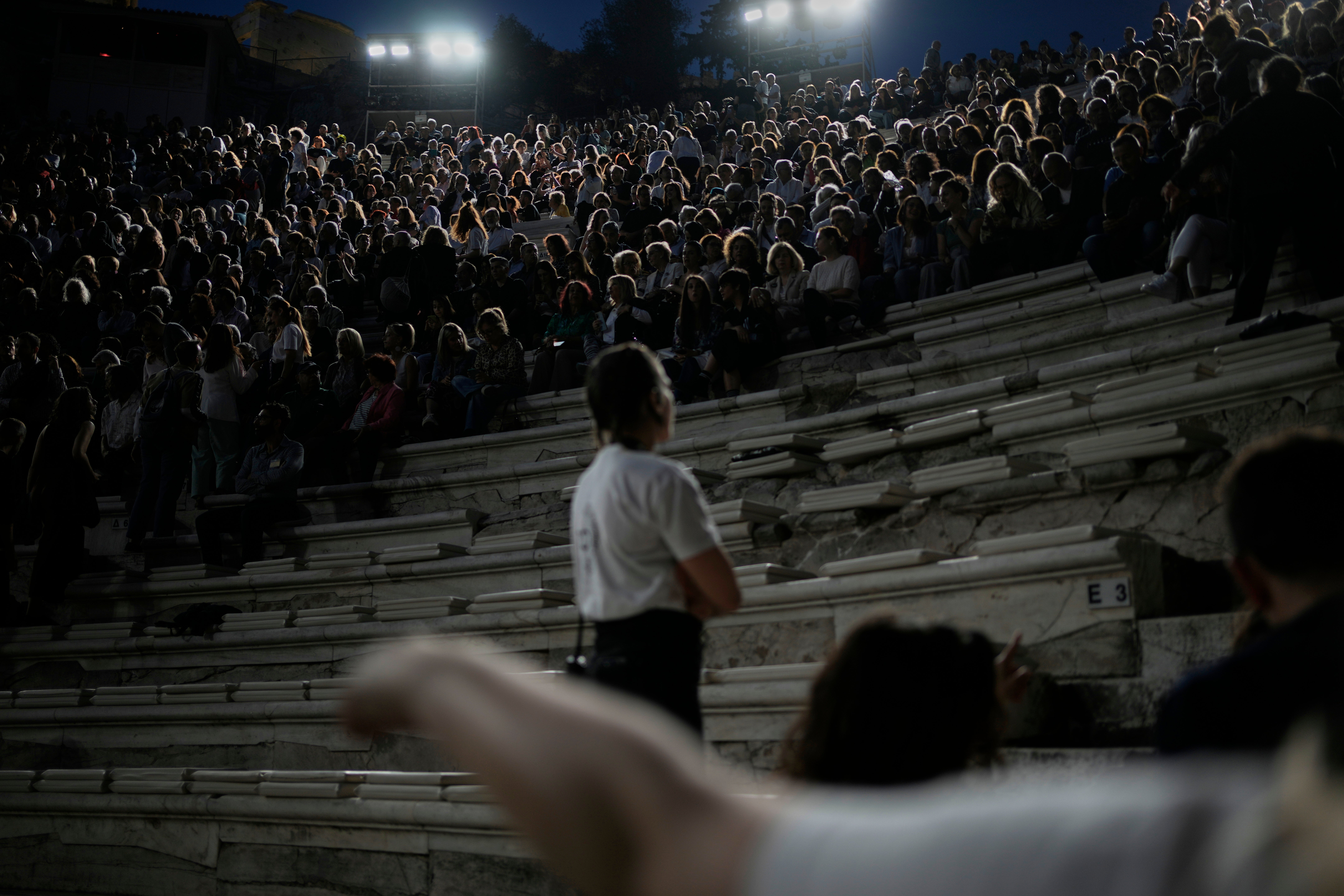 Ushers help spectators taking their seats at the Odeon of Herodes Atticus ahead of Giacomo Puccini's "Turandot" dress rehearsal during the 70th Athens Epidaurus Festival in Athens, Greece, Friday, May 30, 2025. (AP Photo/Thanassis Stavrakis)