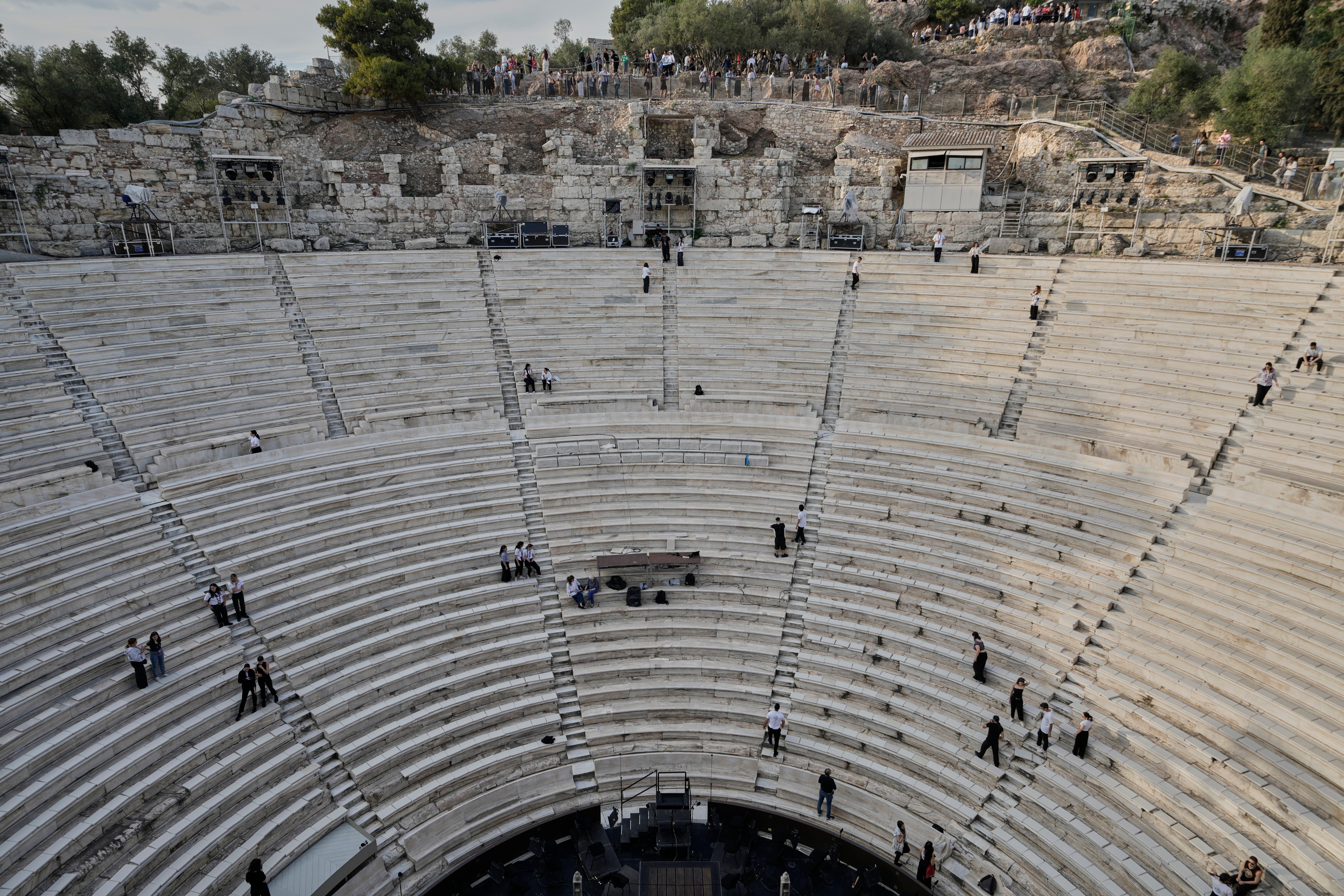 Tourists watch the ushers as they prepare the Odeon of Herodes Atticus ahead of the dress rehearsal of Giacomo Puccini's "Turandot" by the Greek National Opera during the 70th Athens Epidaurus Festival in Athens, Greece, Friday, May 30, 2025. (AP Photo/Thanassis Stavrakis)