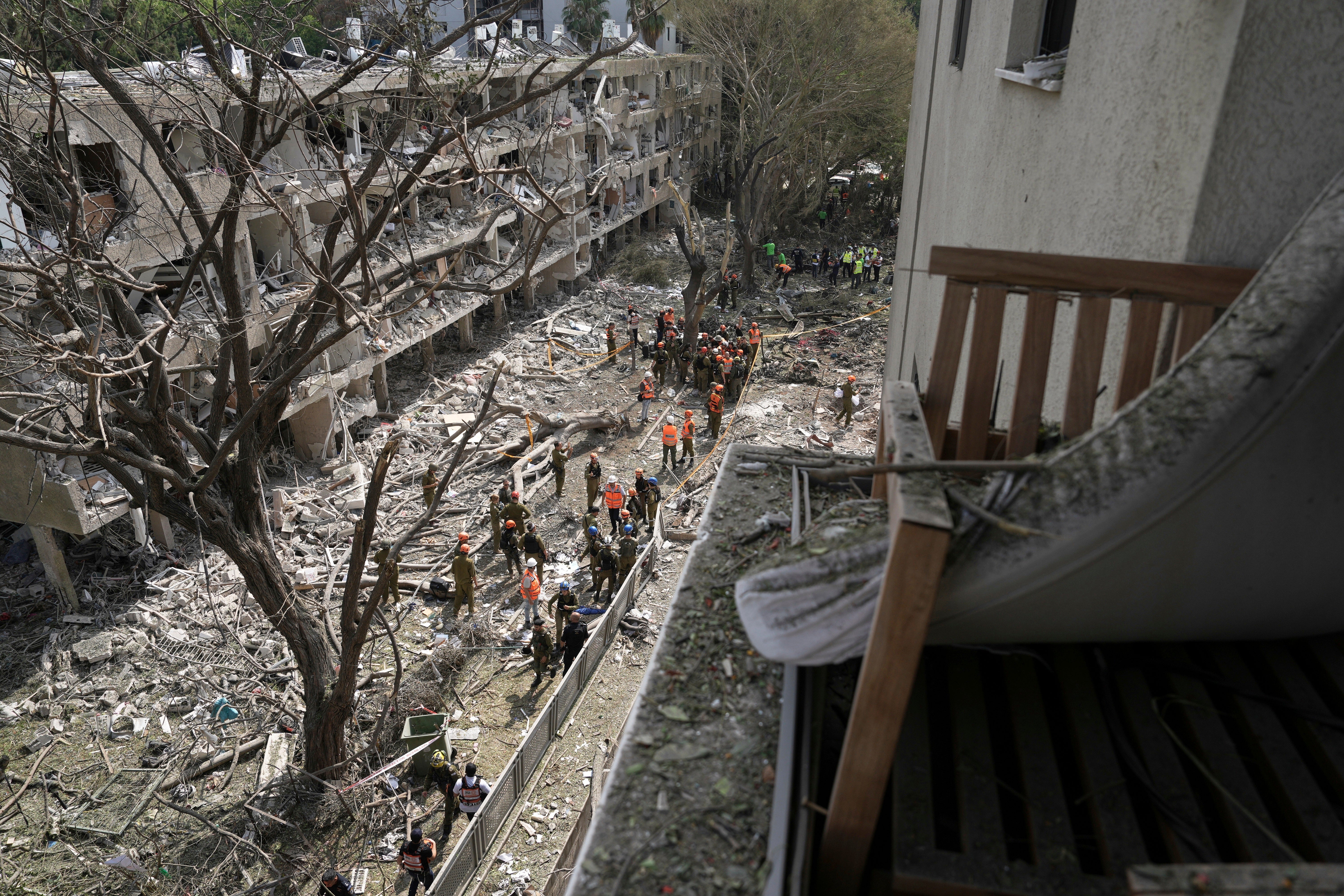 Israel's home front command officers and rescue workers survey the site of a direct missile strike launched from Iran in Tel Aviv