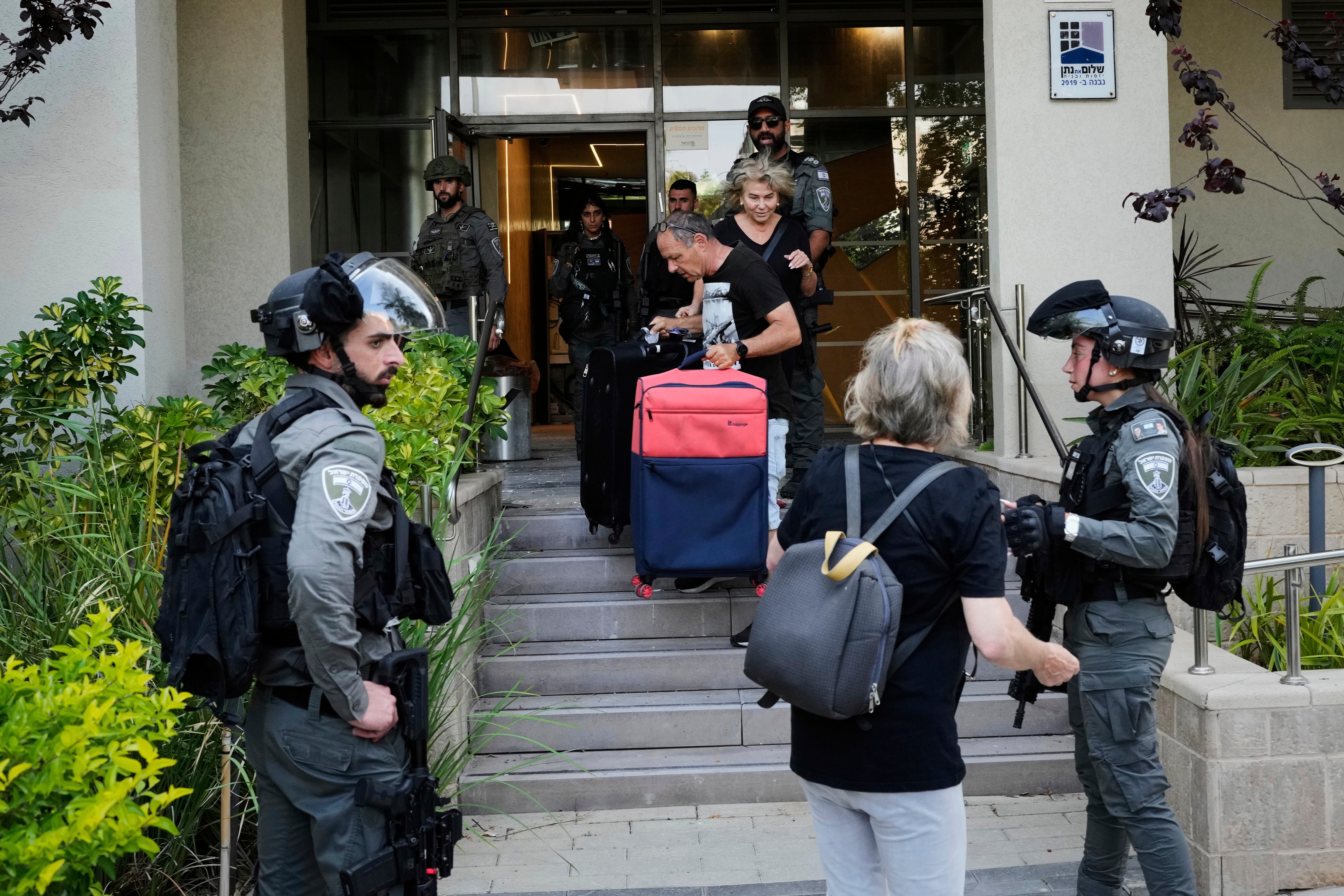 Israeli border police officers help residents evacuate a building damaged in an Iranian missile strike in Tel Aviv, Israel (AP Photo/Bernat Armangue)