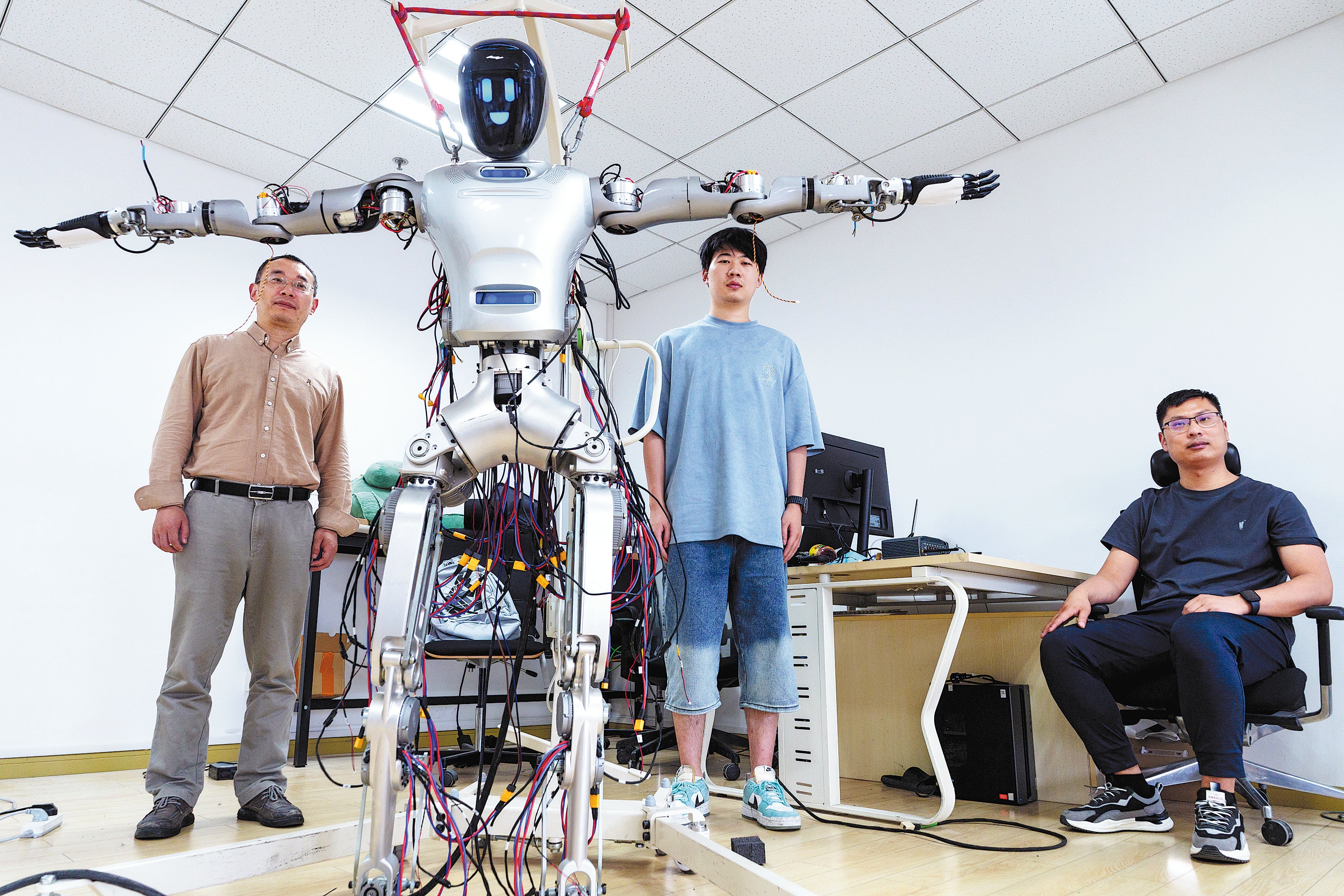 Liu Lizheng (left), head of humanoid robot projects at Fudan University, and his colleagues pose with the Guanghua No 1 humanoid robot on 14 May