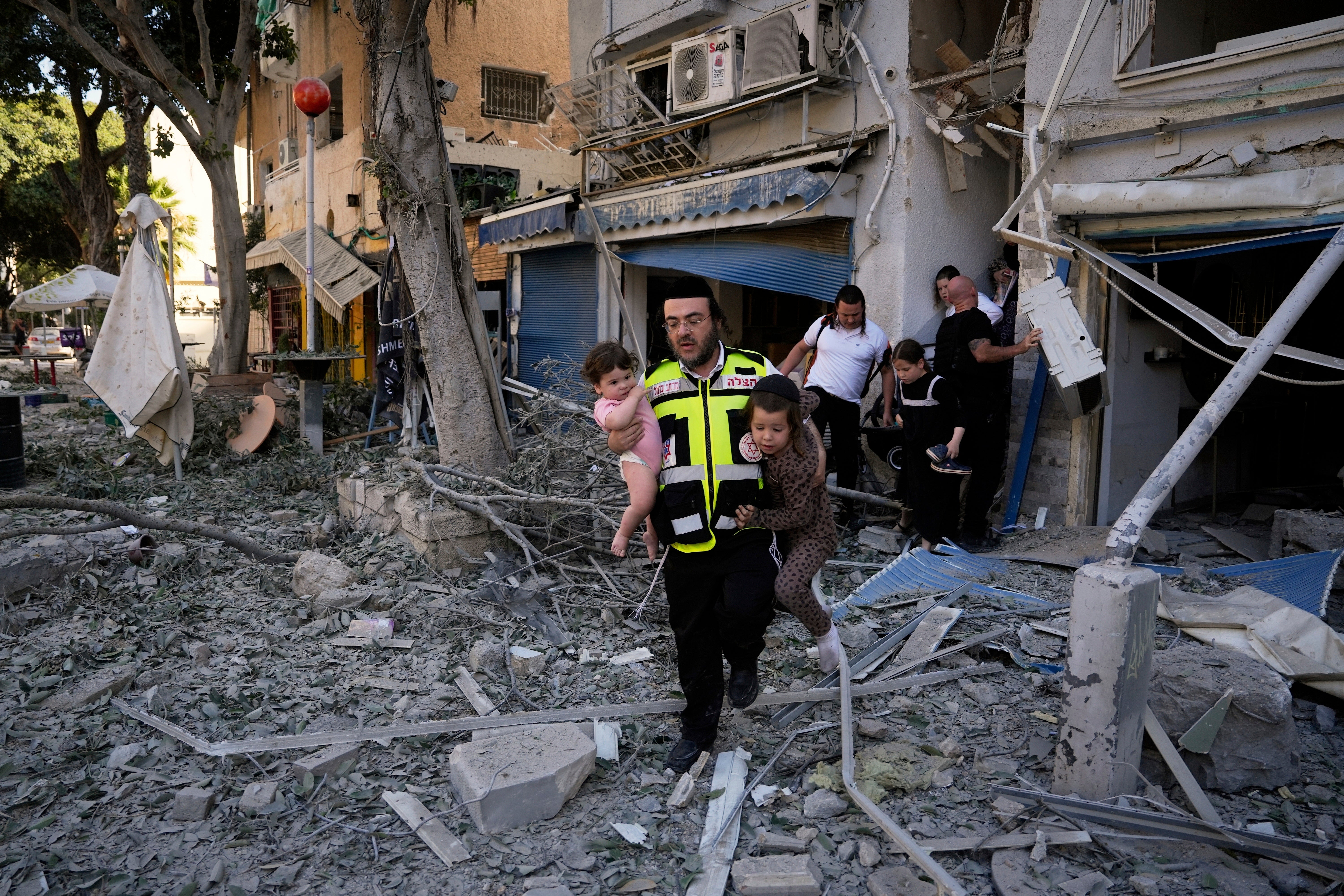 A rescue worker carries away children from the site of an Iranian missile strike in Haifa, Israel