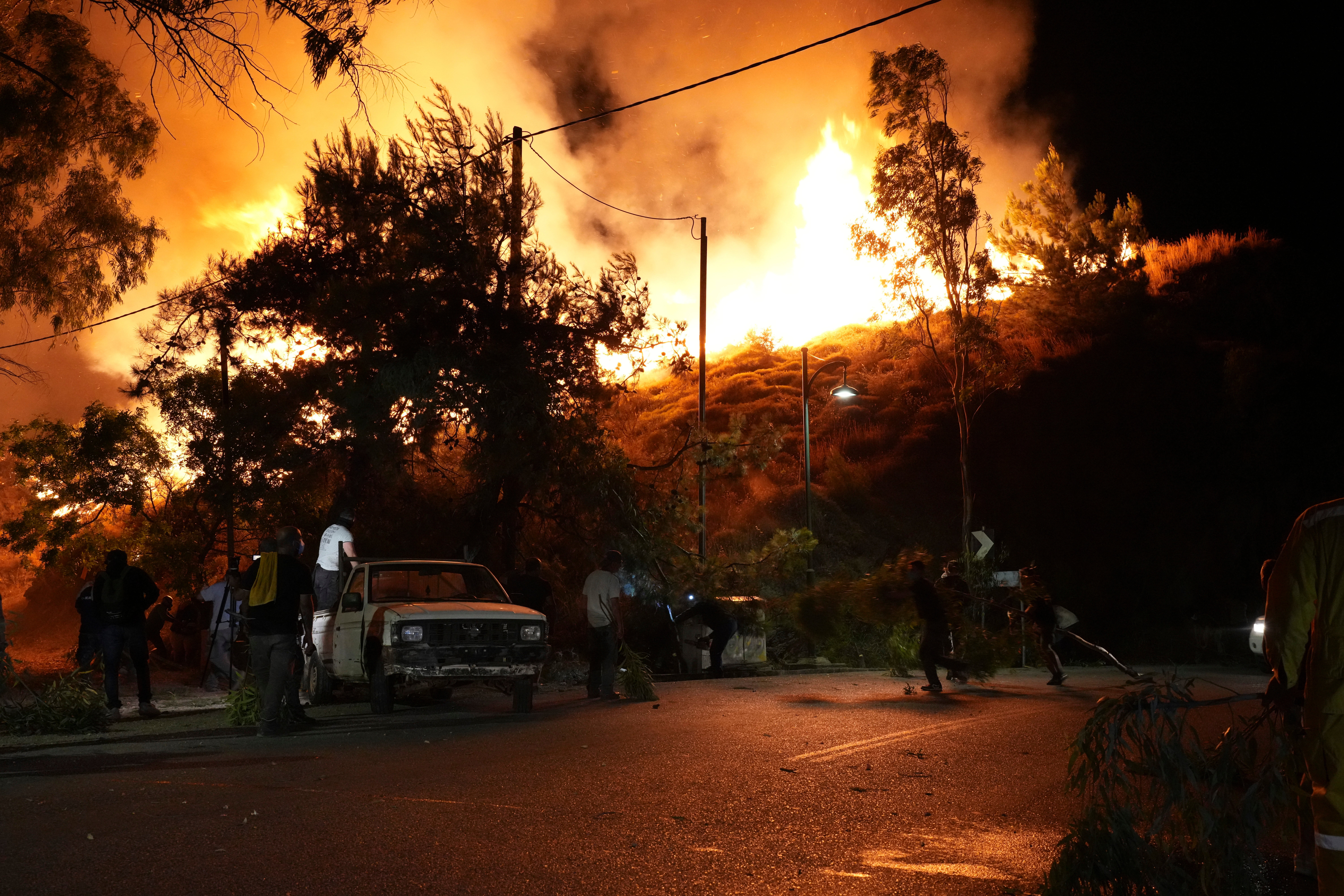 Local residents watch a wildfire approaching in Kofinas, on the eastern Aegean island of Chios, Greece, late Sunday, 22 June