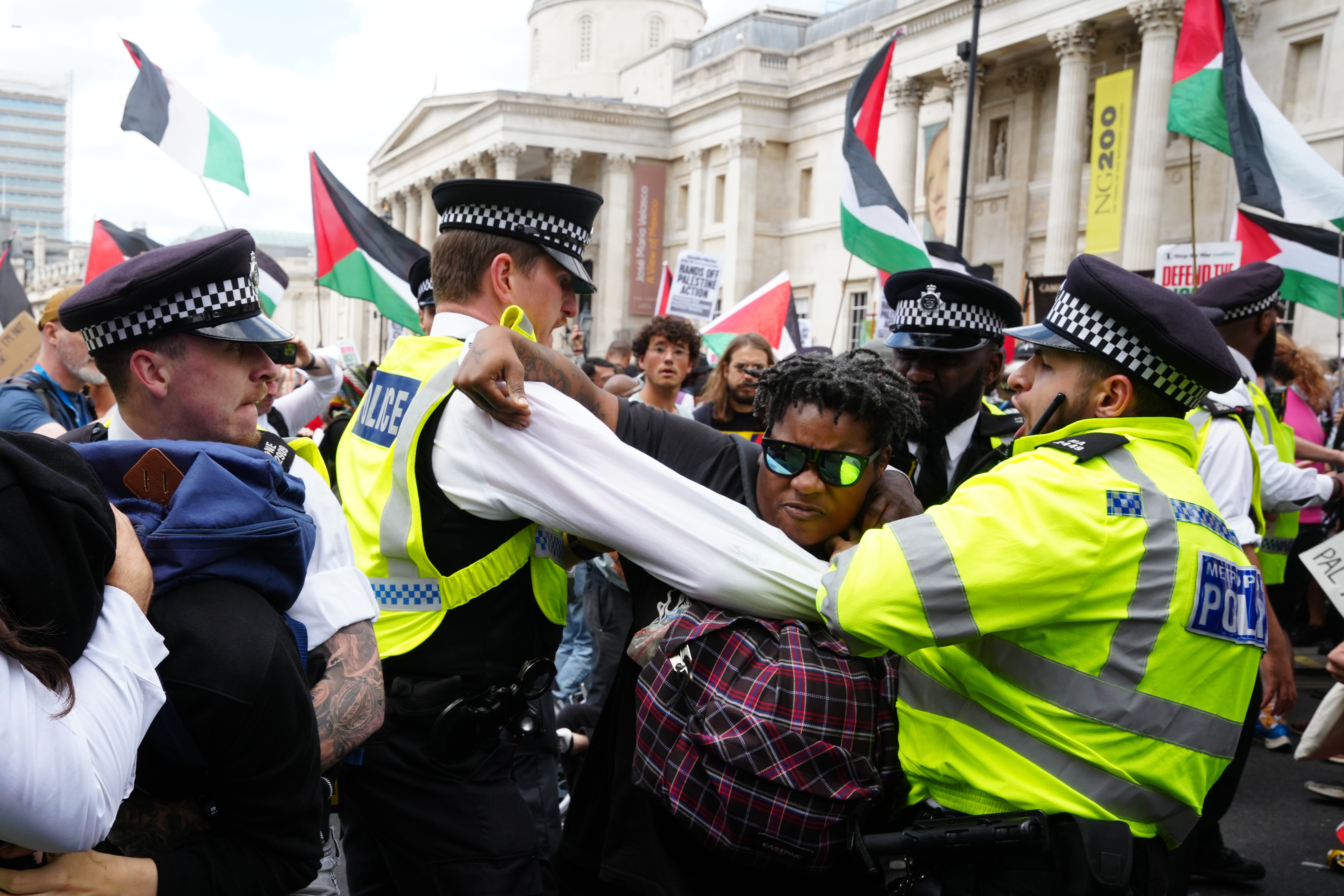 Police officers holding back protesters at Trafalgar Square