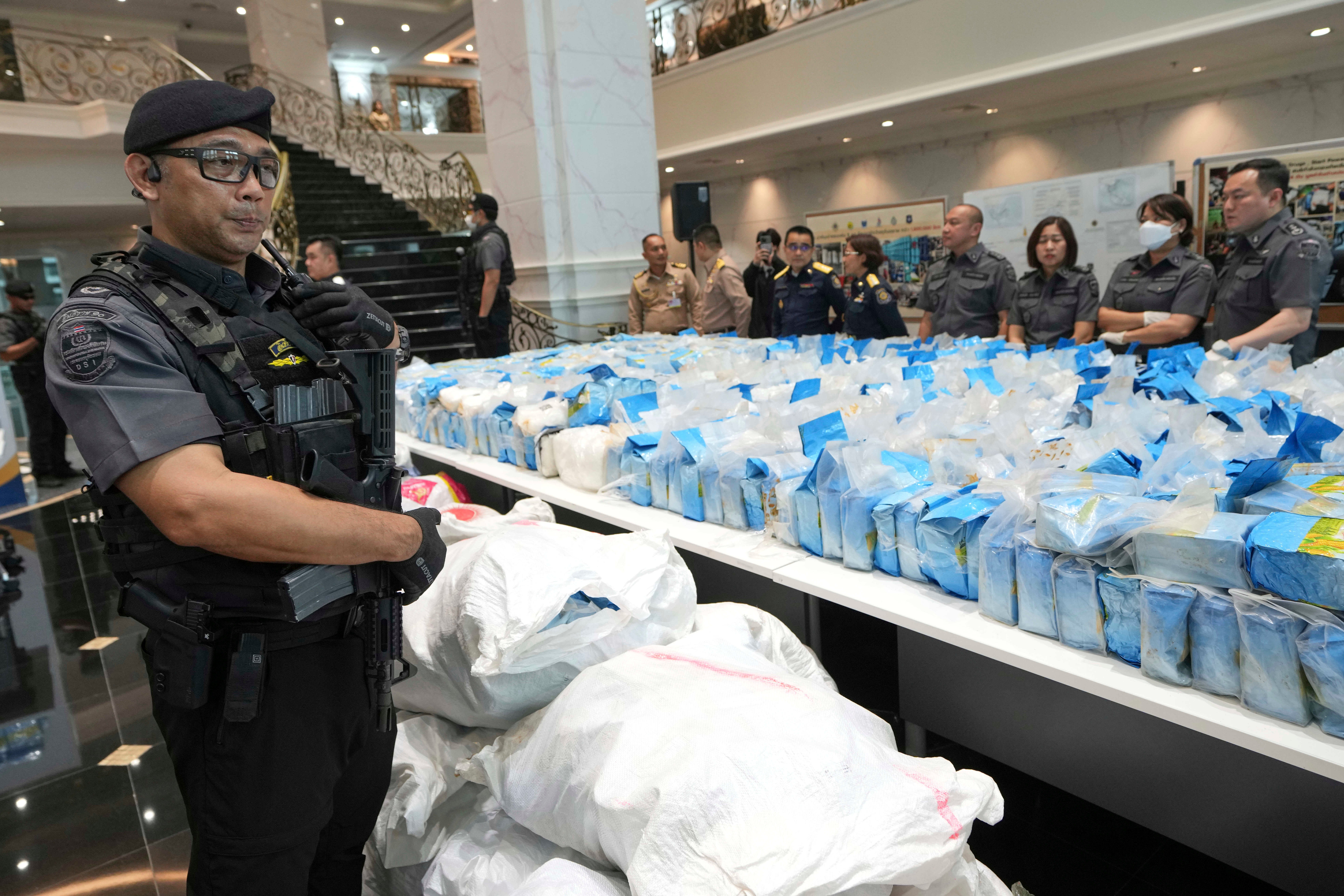 Department of Special Investigation officers stand guard near packages of nearly 2.4 tons of crystal methamphetamine, which were disguised as bags of corn flour, during a news conference in Bangkok, Thailand, Monday, June 23, 2025. (AP Photo/Sakchai Lalit)