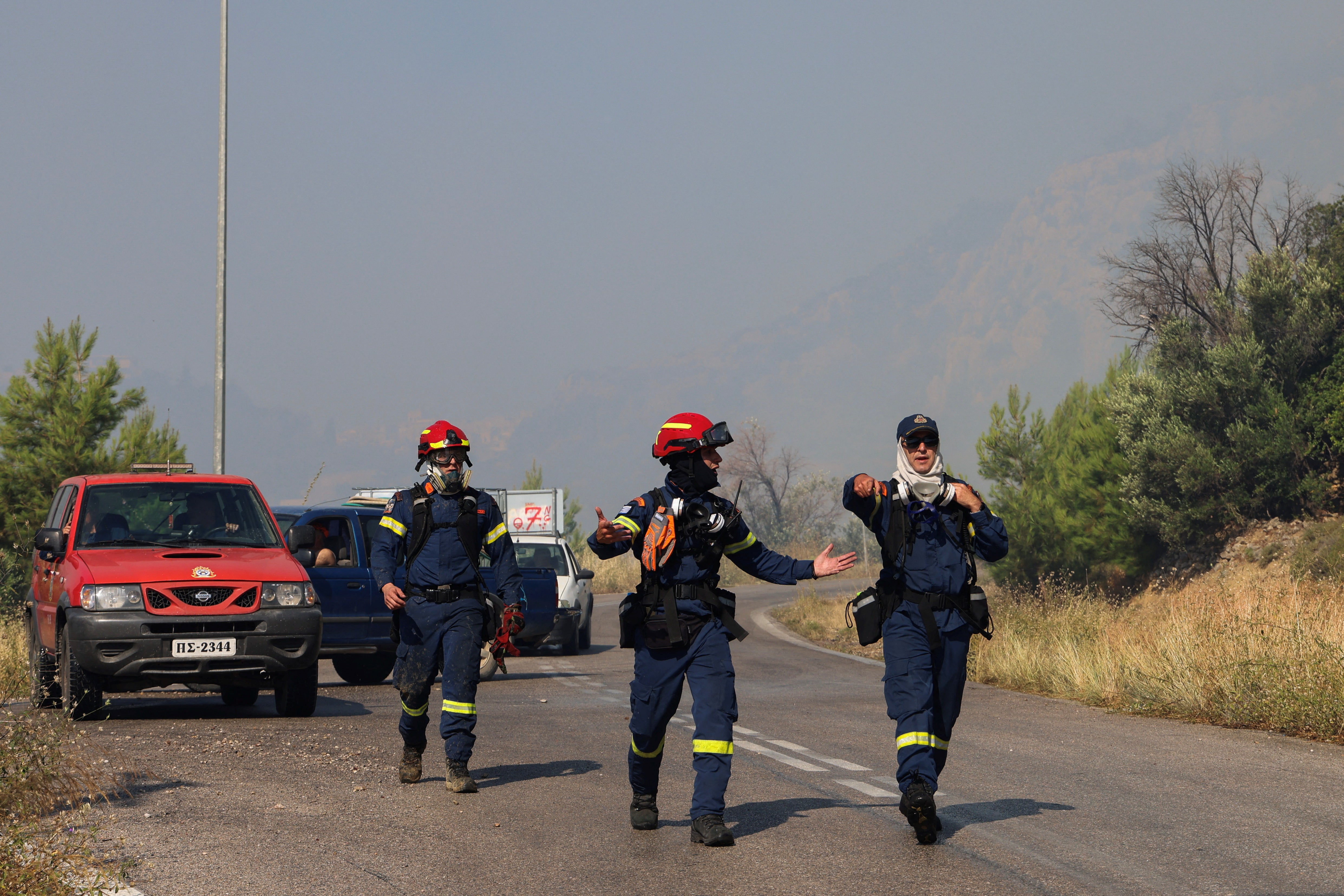 Firefighters prepare to operate as a wildfire burns on Chios island