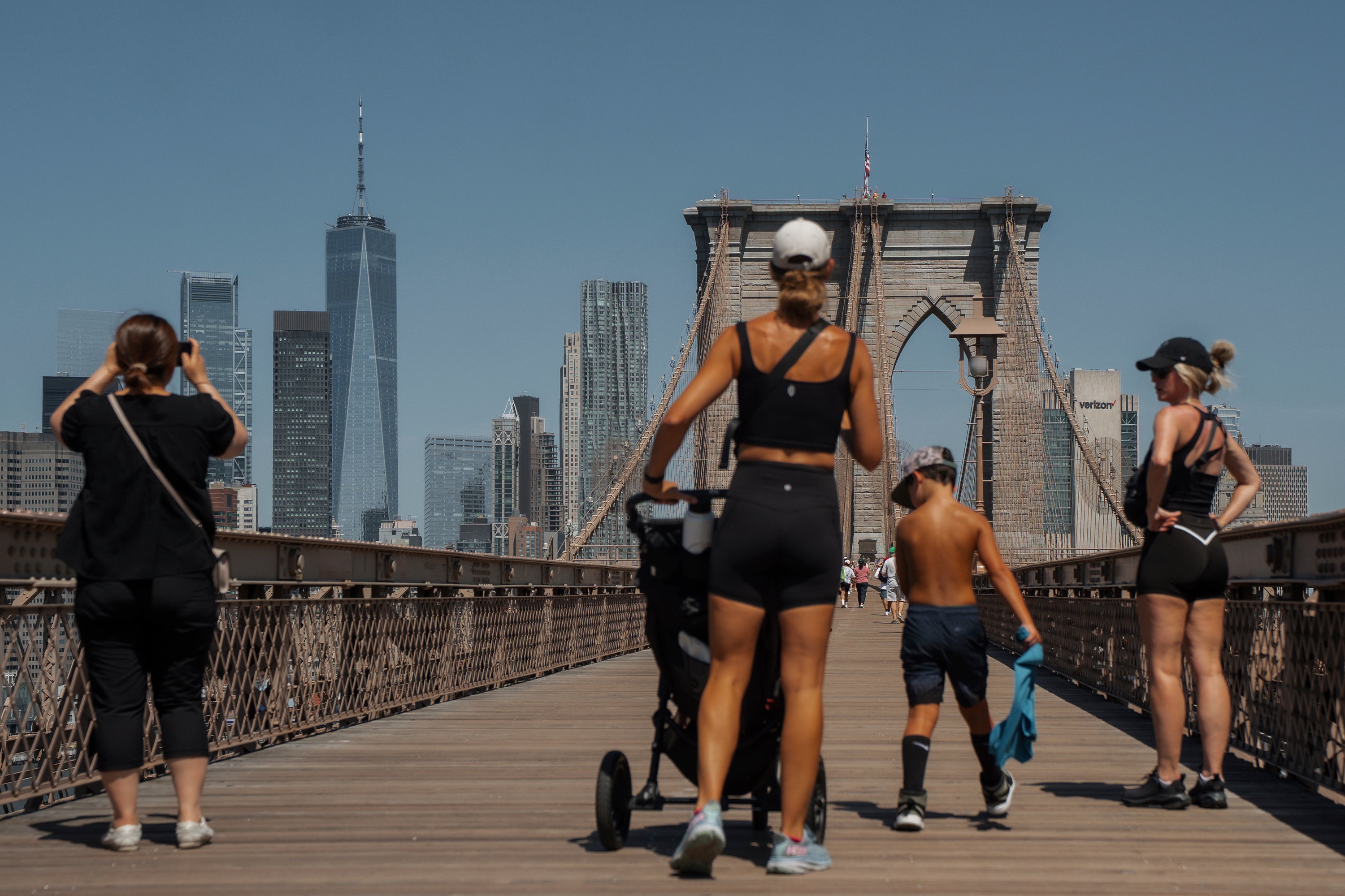 People stand on the Brooklyn bridge on Tuesday, as temperatures hit triple figures for the first time since 2013