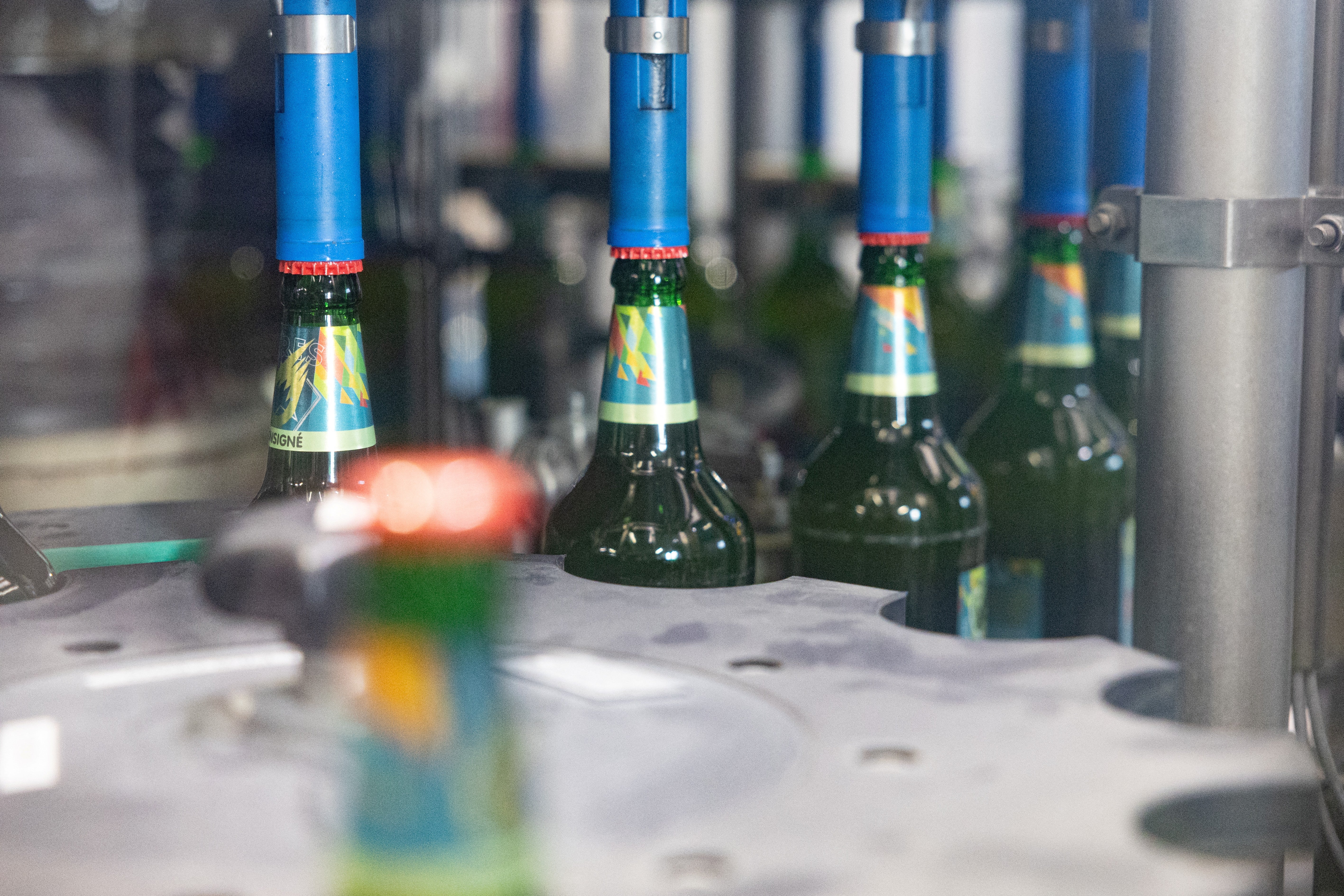 Machine placing caps on beer bottles on an assembly line