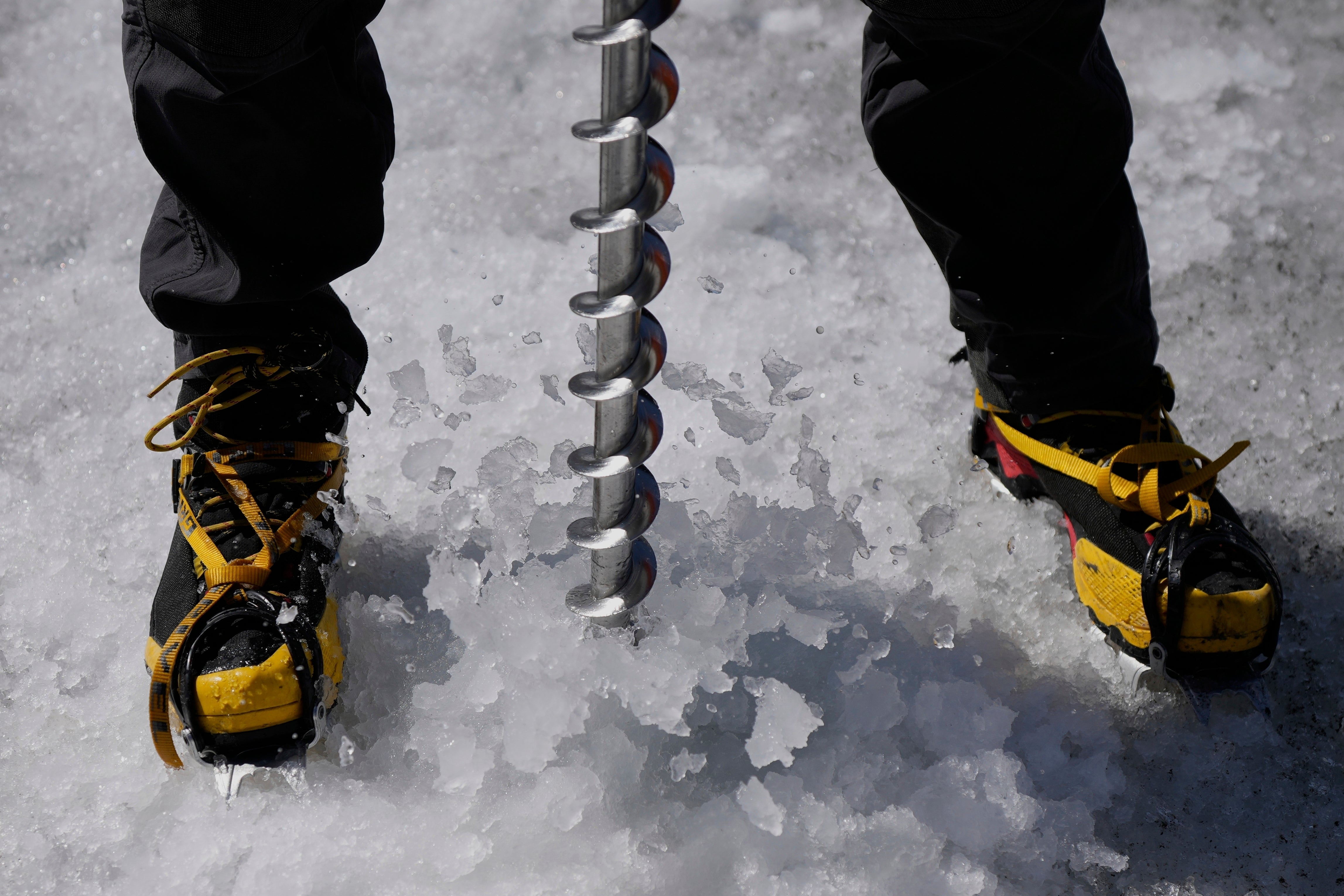 Matthias Huss, of the Federal Institute of Technology in Zurich and glacier monitoring group GLAMOS, drills holes into the Rhone Glacier near Goms, Switzerland, June 10, 2025. (AP Photo/Matthias Schrader)