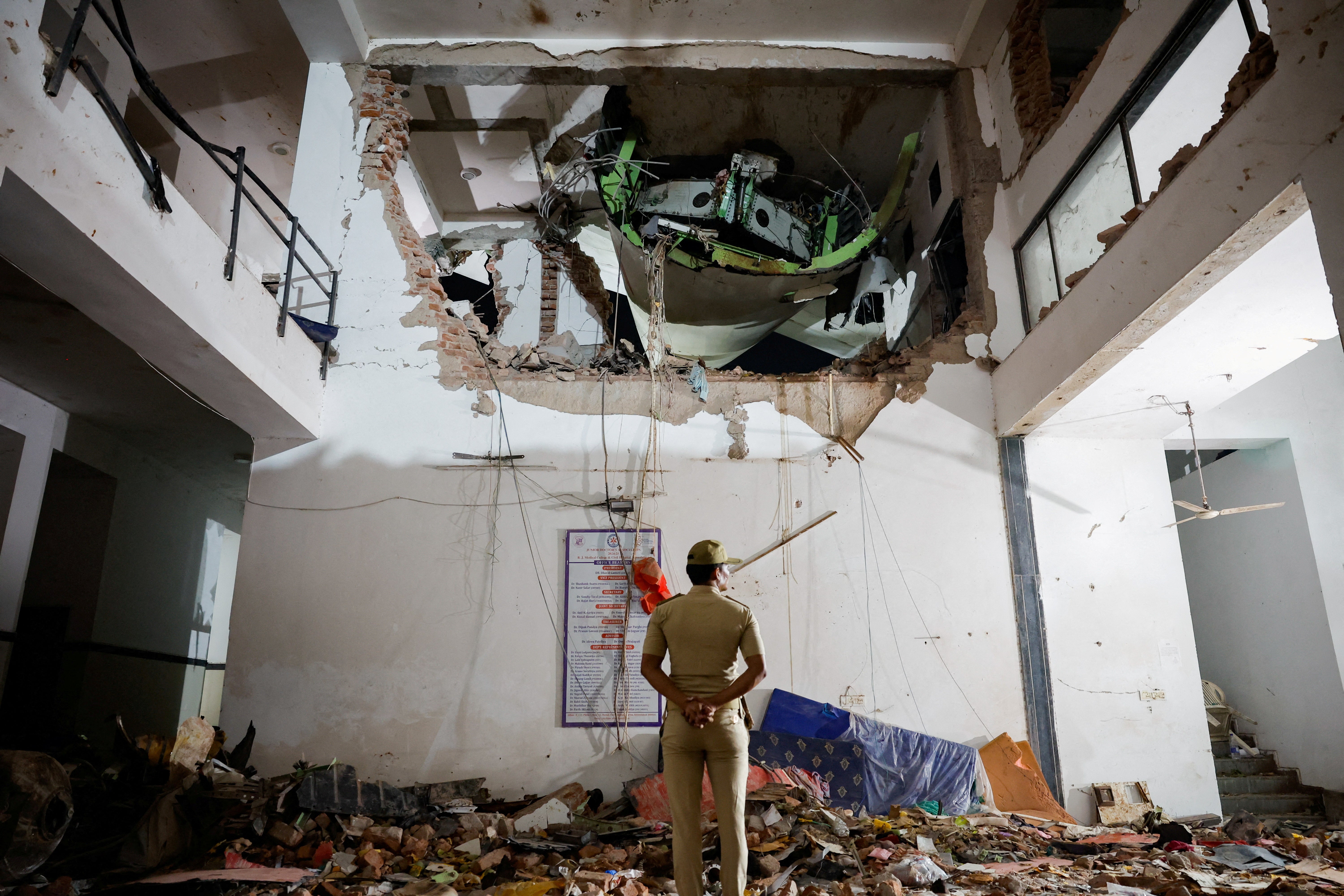 A police officer stands in front of the wreckage of an Air India aircraft