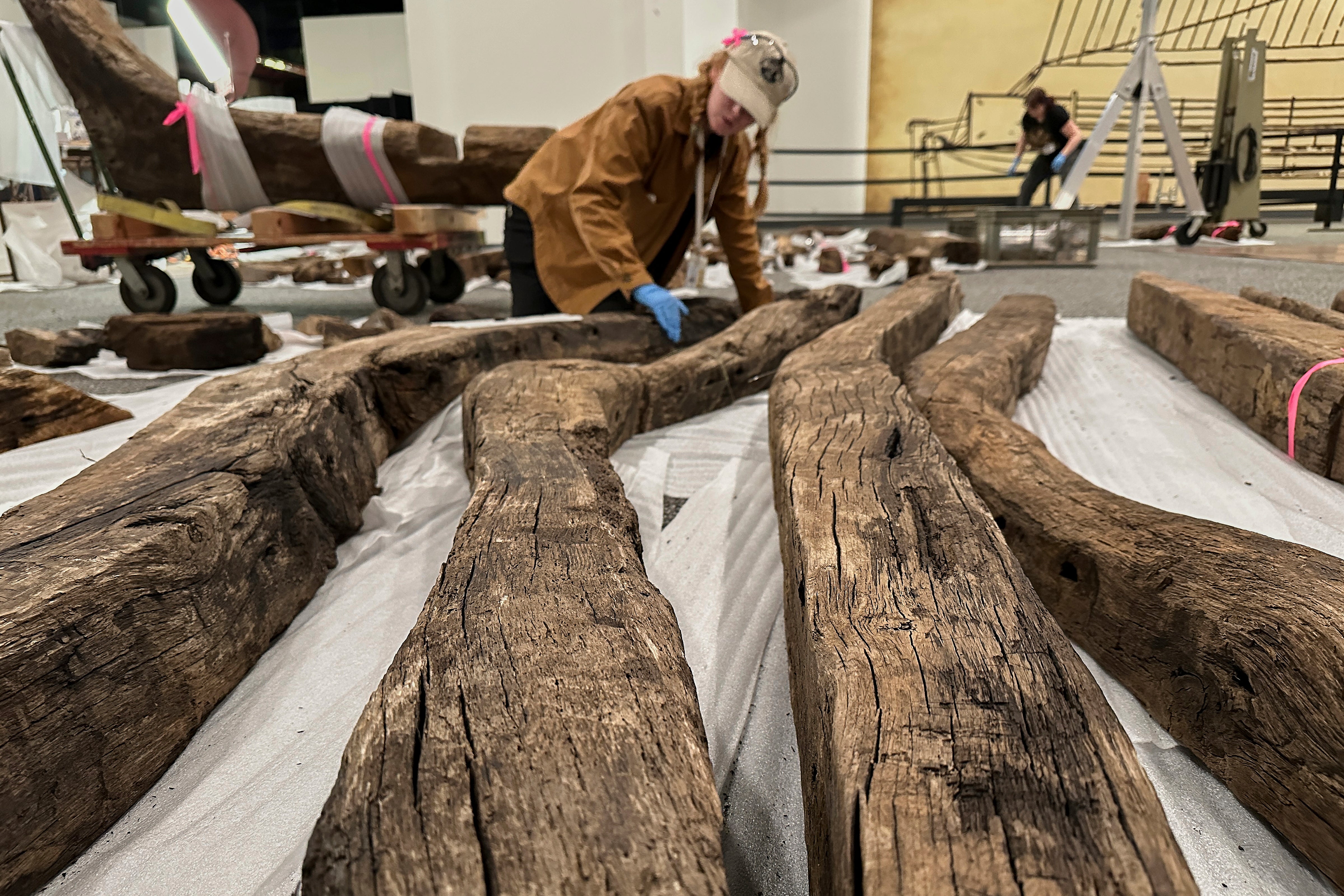 Research assistant Alyssa Carpenter inspects timbers from of a wooden Revolutionary War-era gunboat to prepare for the craft's partial reconstruction at the New York State Museum