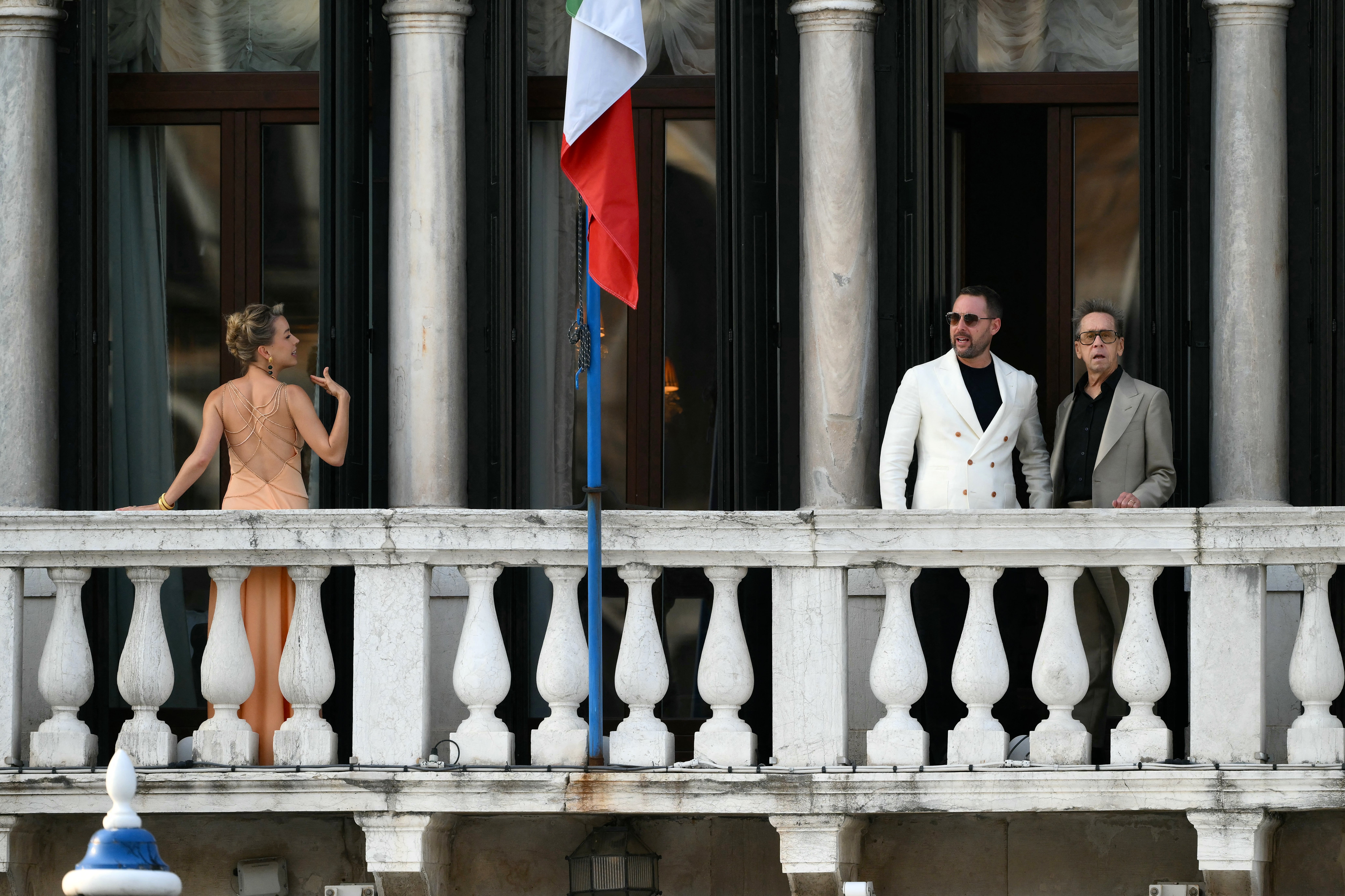 Lydia Kives (L), Michael Kives and US film producer Brian Grazer (R) standing on a balcony of the Gritti Palace