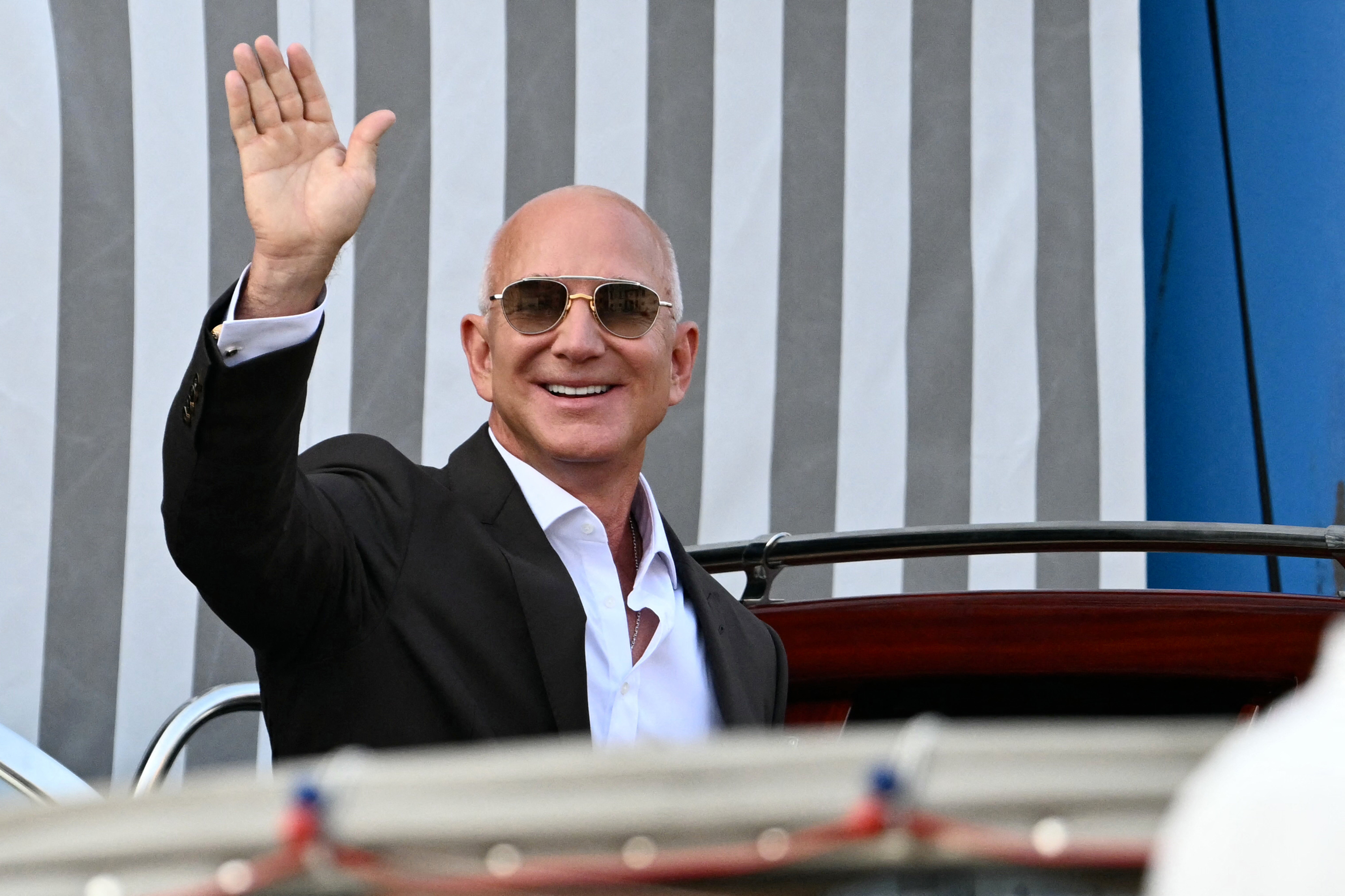 Amazon's founder Jeff Bezos waves as he gets on a taxi boat at the Aman Hotel in Venice