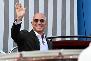 Amazon's founder Jeff Bezos waves as he gets on a taxi boat at the Aman Hotel in Venice