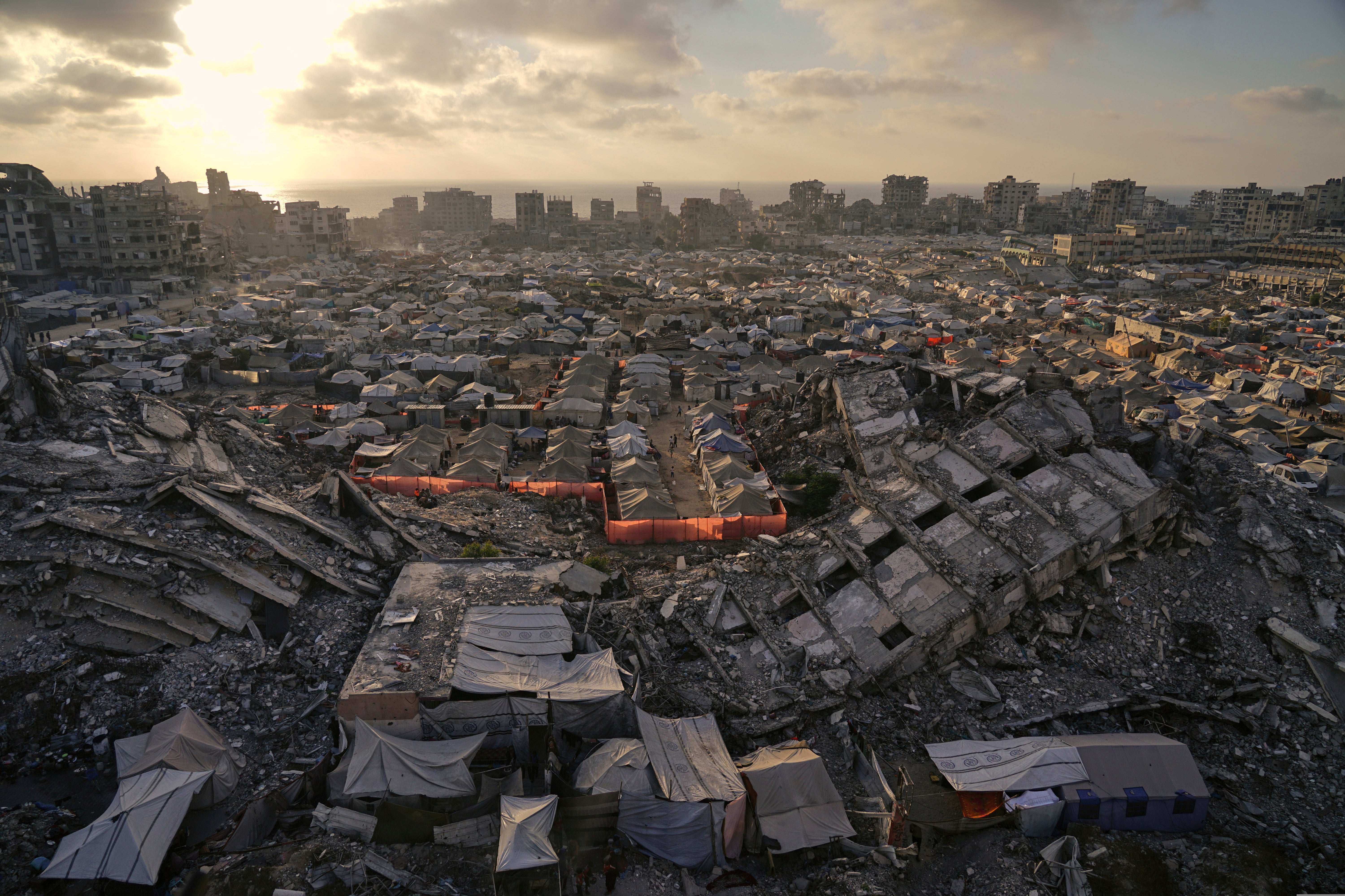 A tent camp for displaced Palestinians stretches among the ruins of buildings destroyed by Israeli bombardments in the west of Gaza City, Saturday, 21 June
