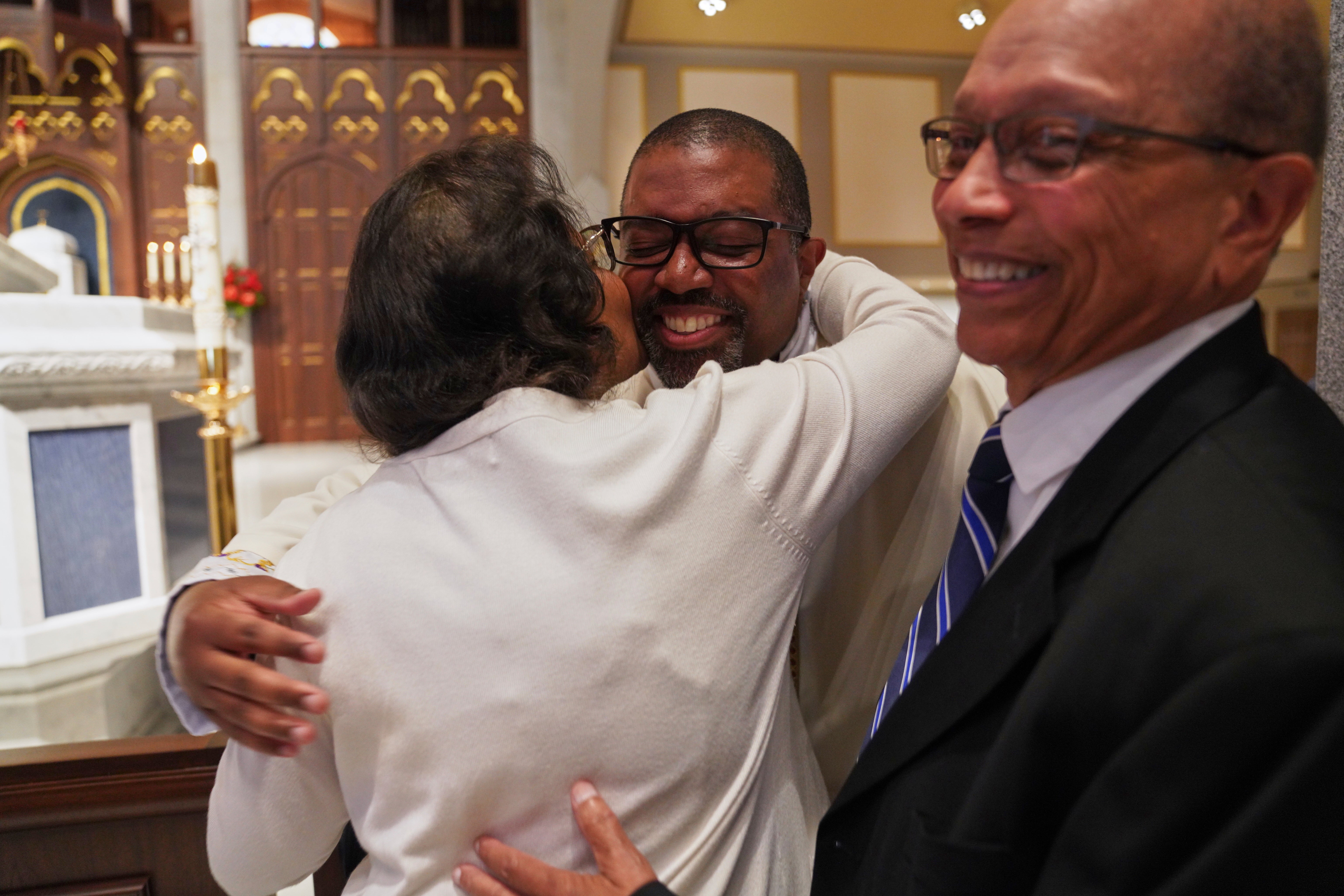 The Rev. Ricky Malebranche, center, hugs his parents, Margaret and Jacques Malebranche, after being ordained a priest at the Cathedral of Saint Thomas More in Arlington
