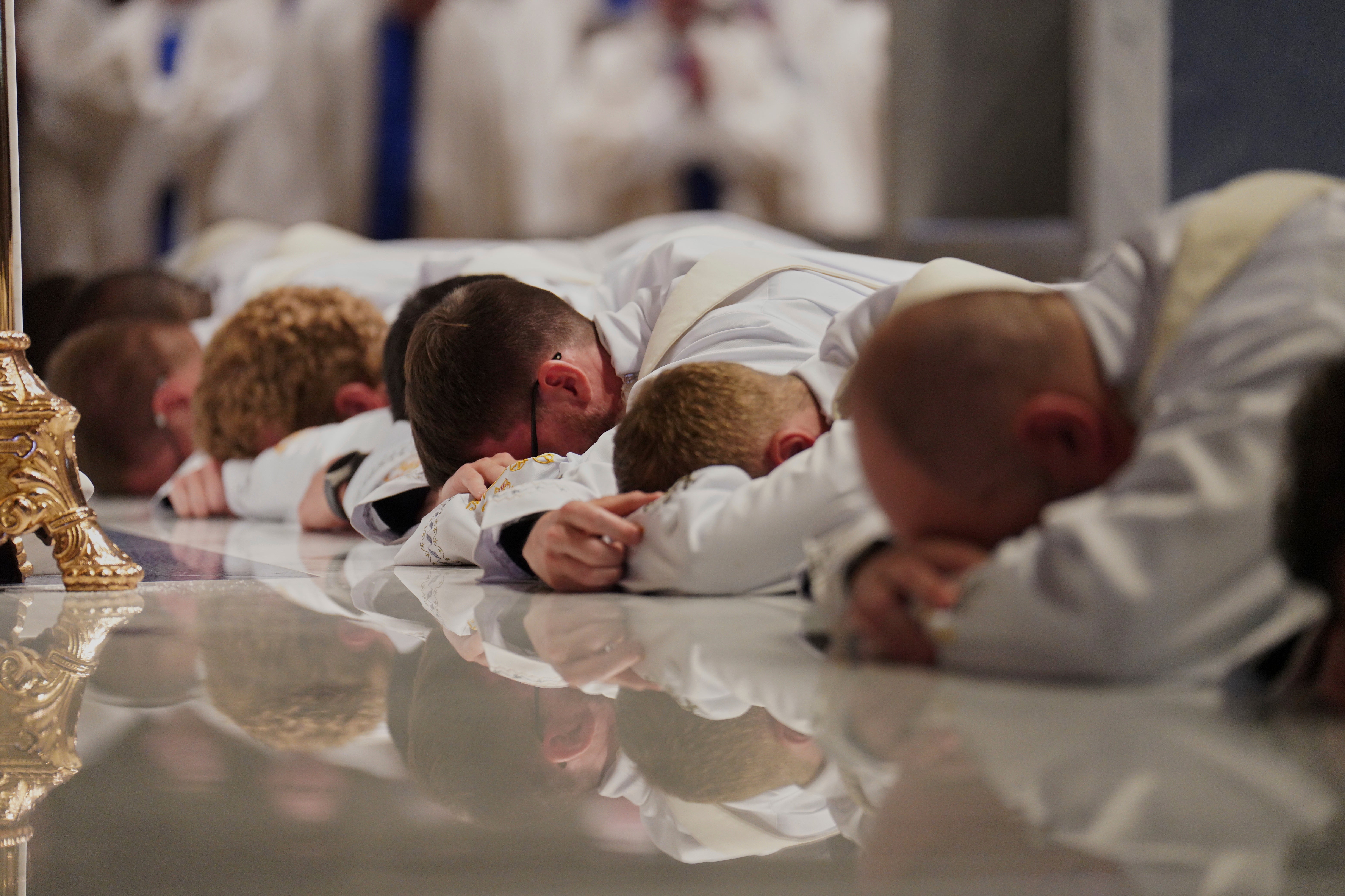 Twelve deacons prostrate in front of the altar at the Cathedral of Saint Thomas More during their ordination Mass in Arlington