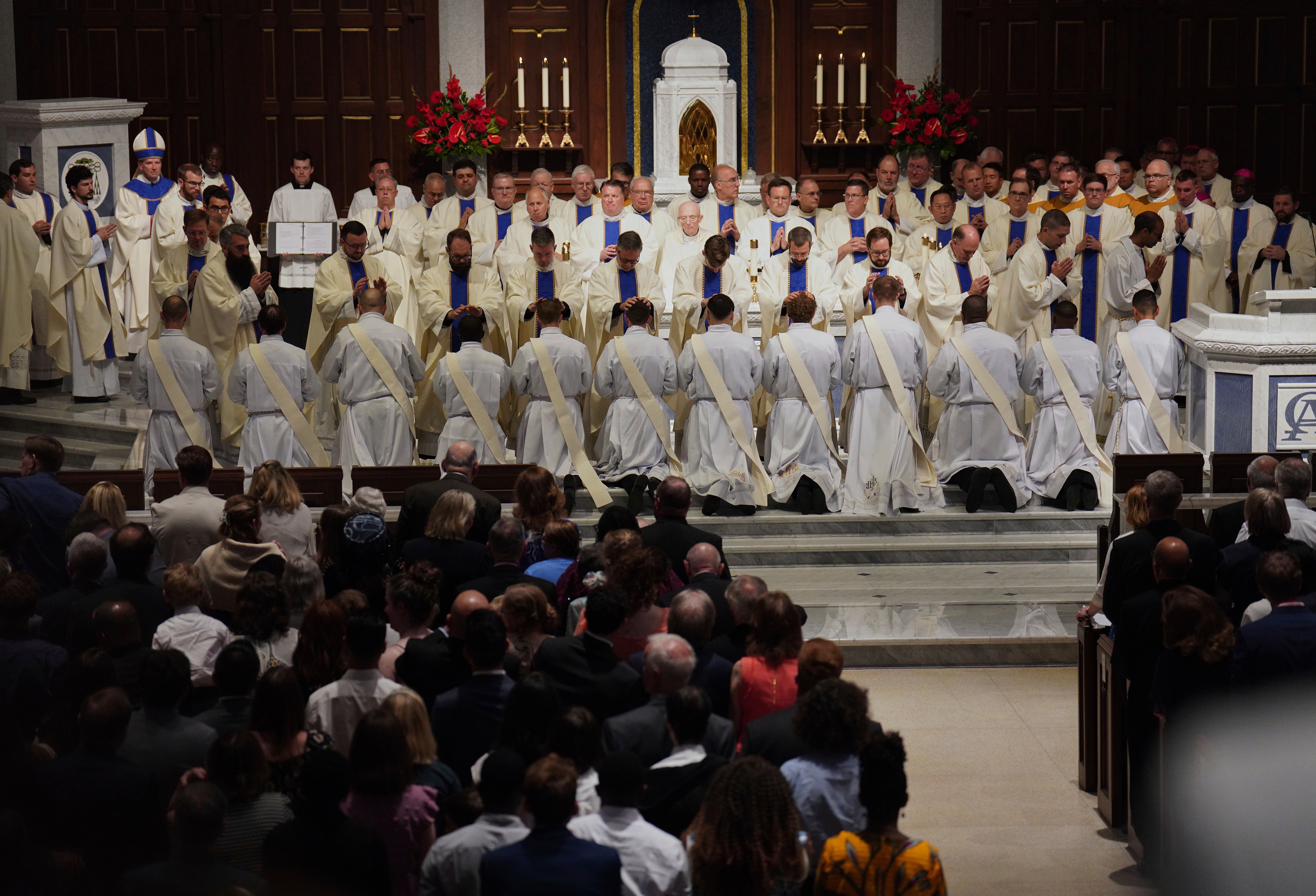 Priests and bishops bless the 12 newly ordained priests during Mass at the Cathedral of Saint Thomas More in Arlington