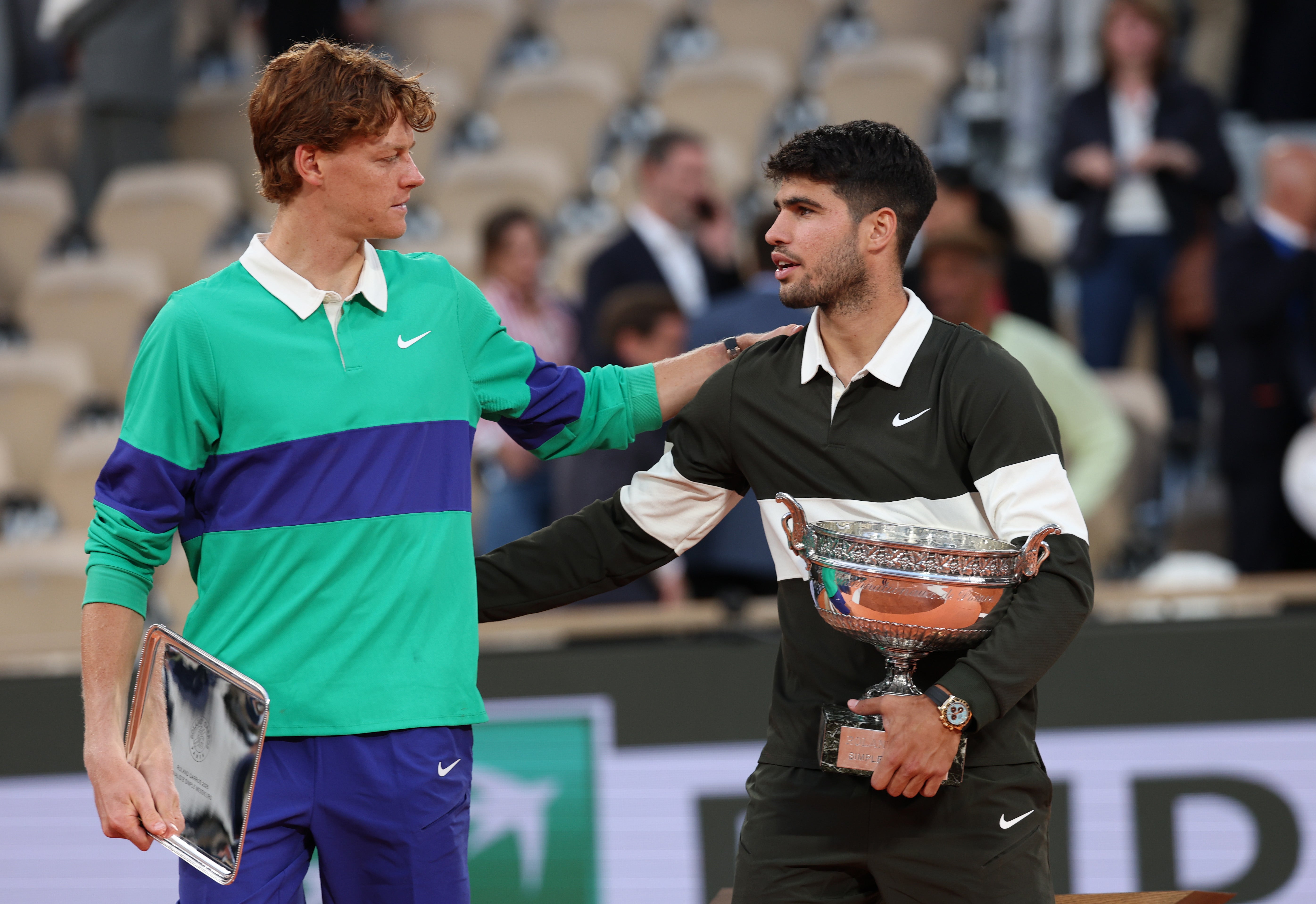 Carlos Alcaraz, right, holds the Coupe des Mousquetaires trophy at the French Open as he speaks with runner-up Jannik Sinner