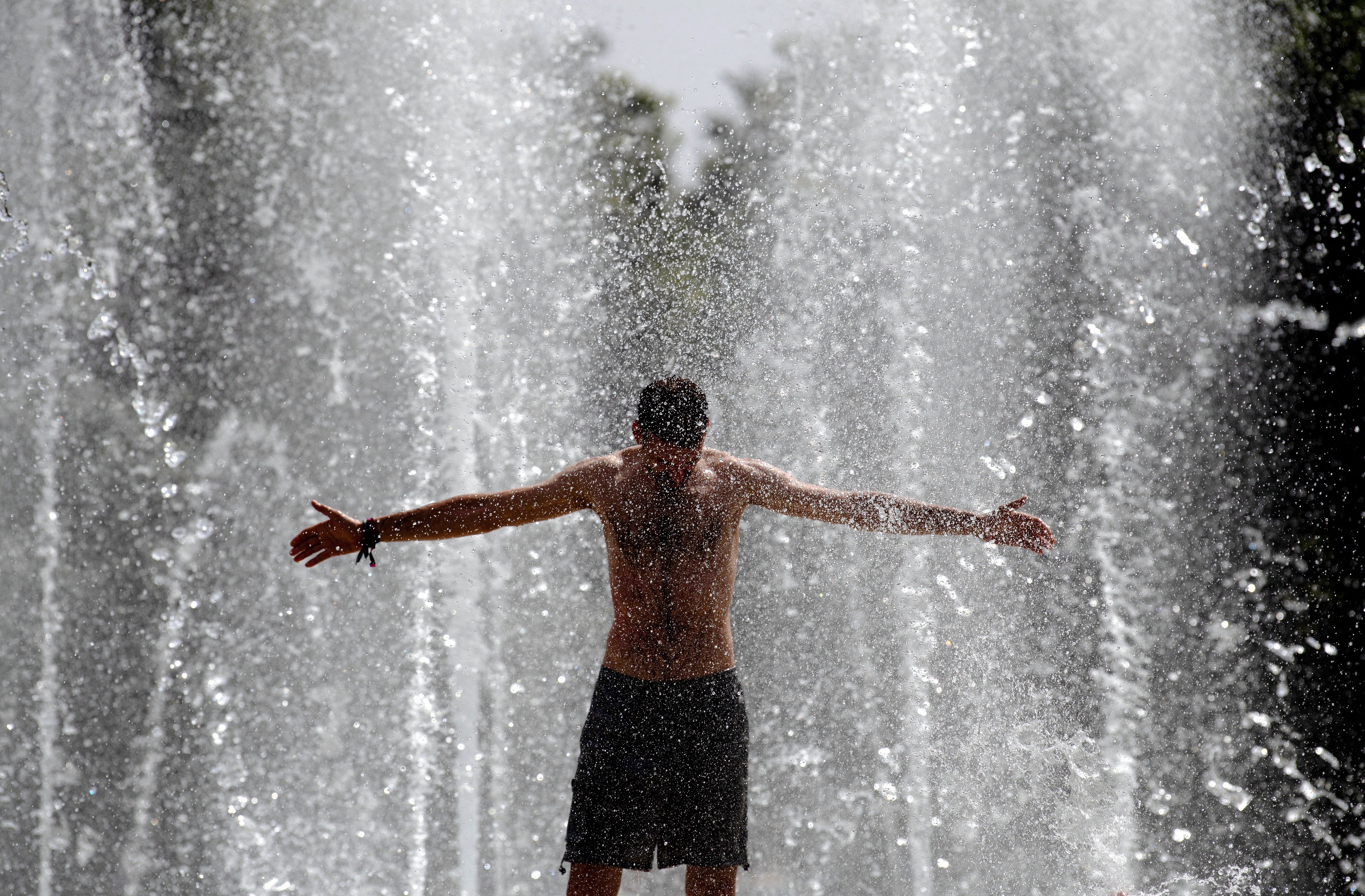A man cools off in a fountain in Seville