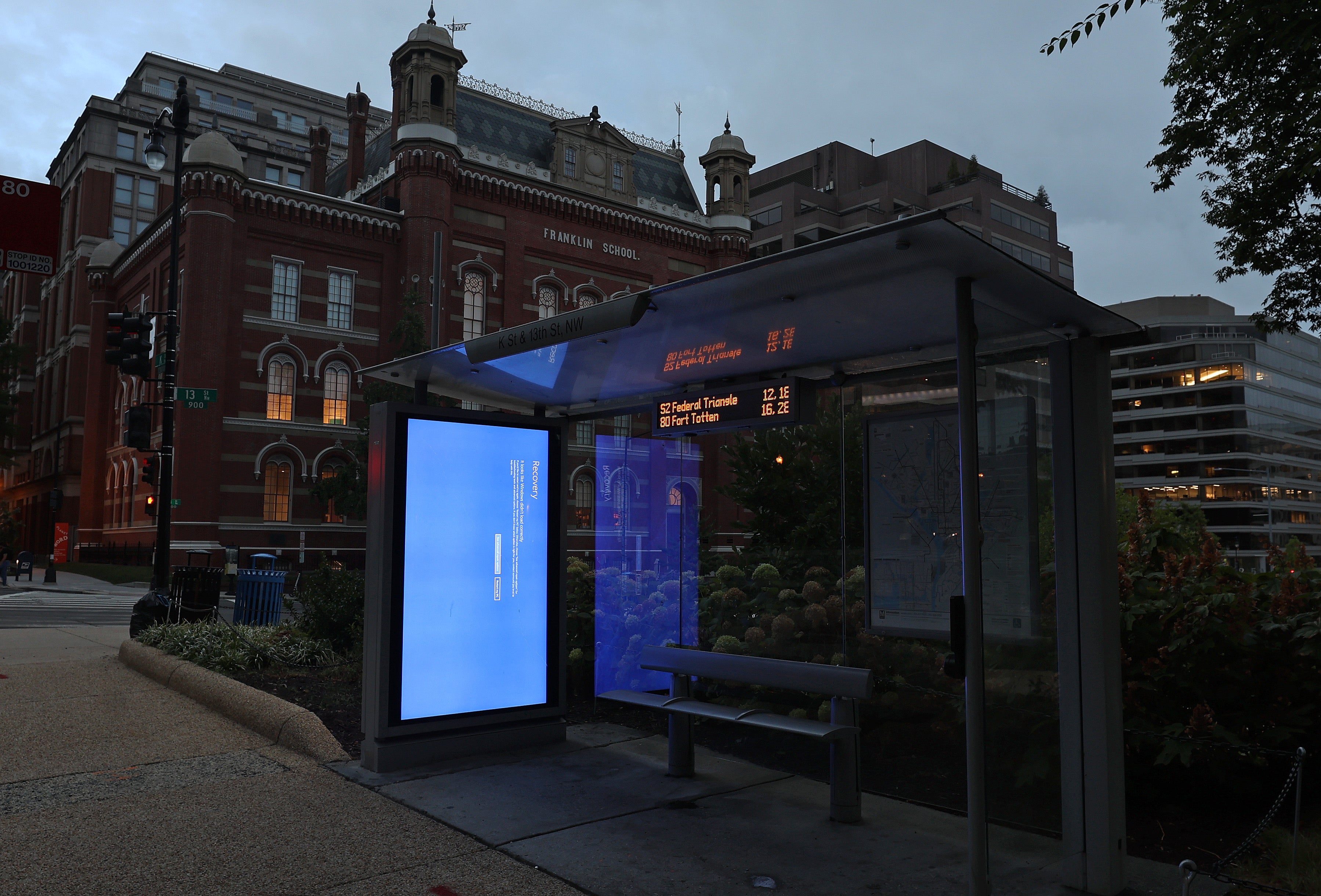 A blue Windows error message caused by the CrowdStrike software update is displayed on a screen in a bus shelter