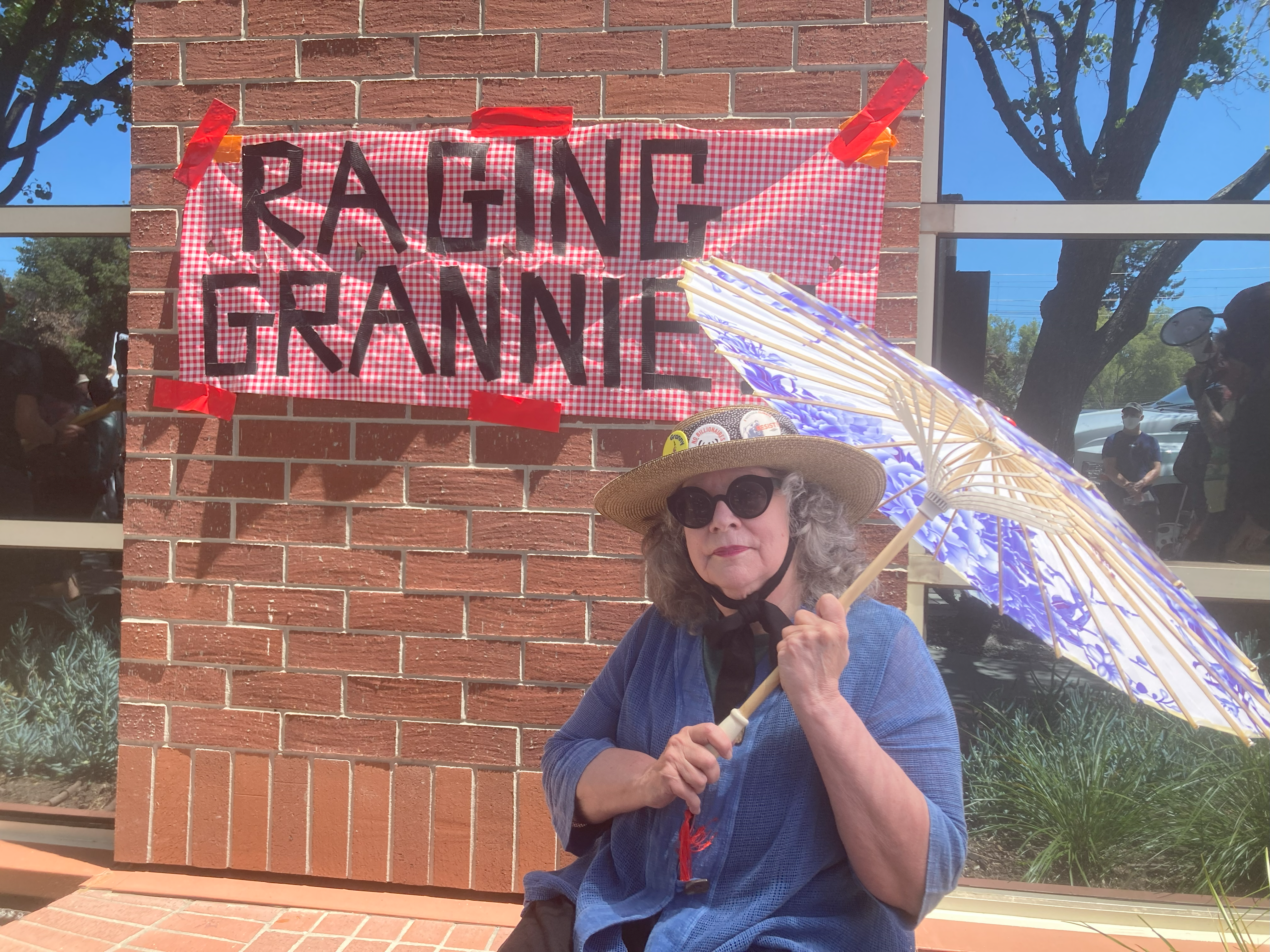 Ruth Robertson, 72, a member of the Raging Grannies protest group, shades herself against the blazing Silicon Valley sun