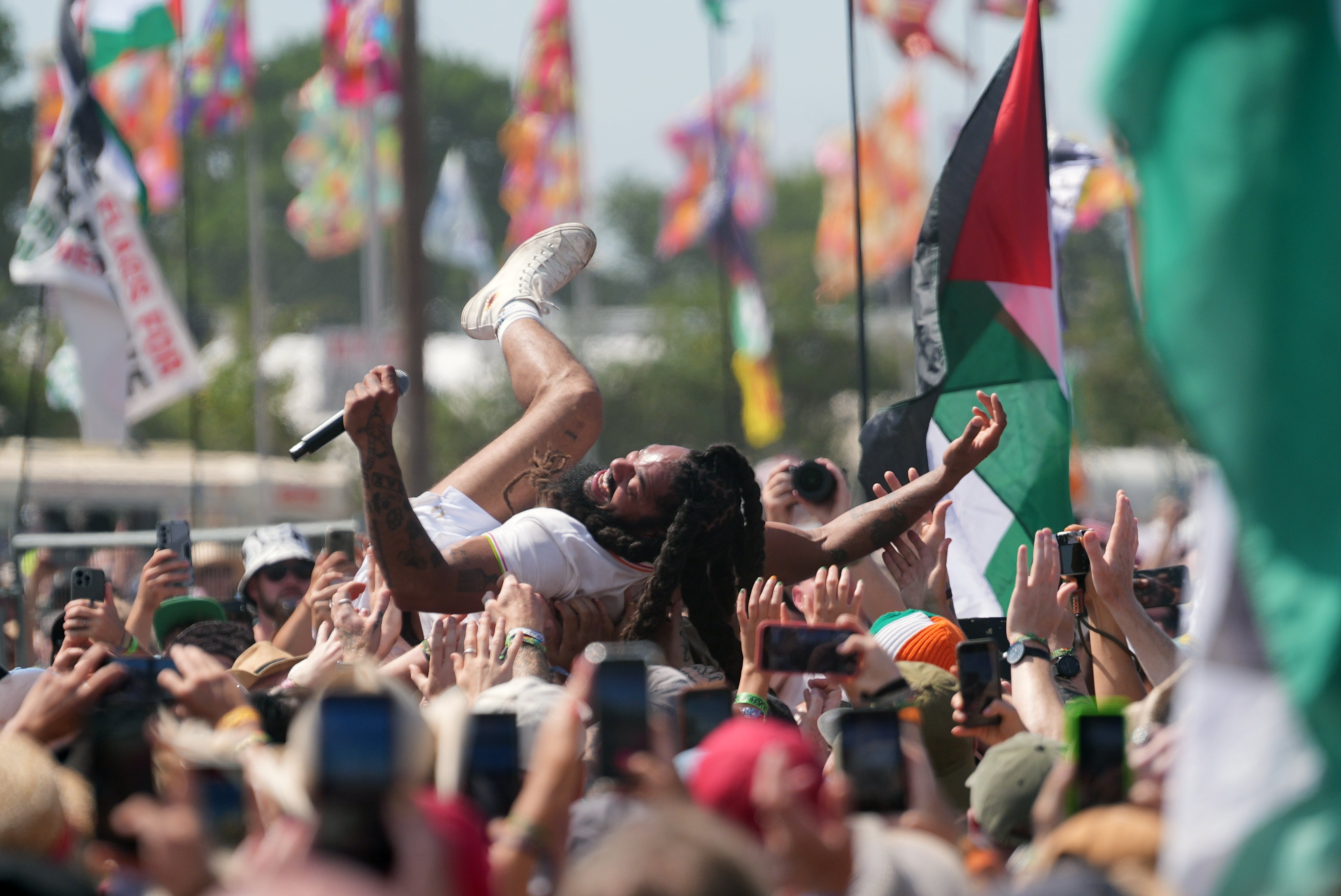 A Bob Vylan member crowd-surfs surrounded by Palestinian flags