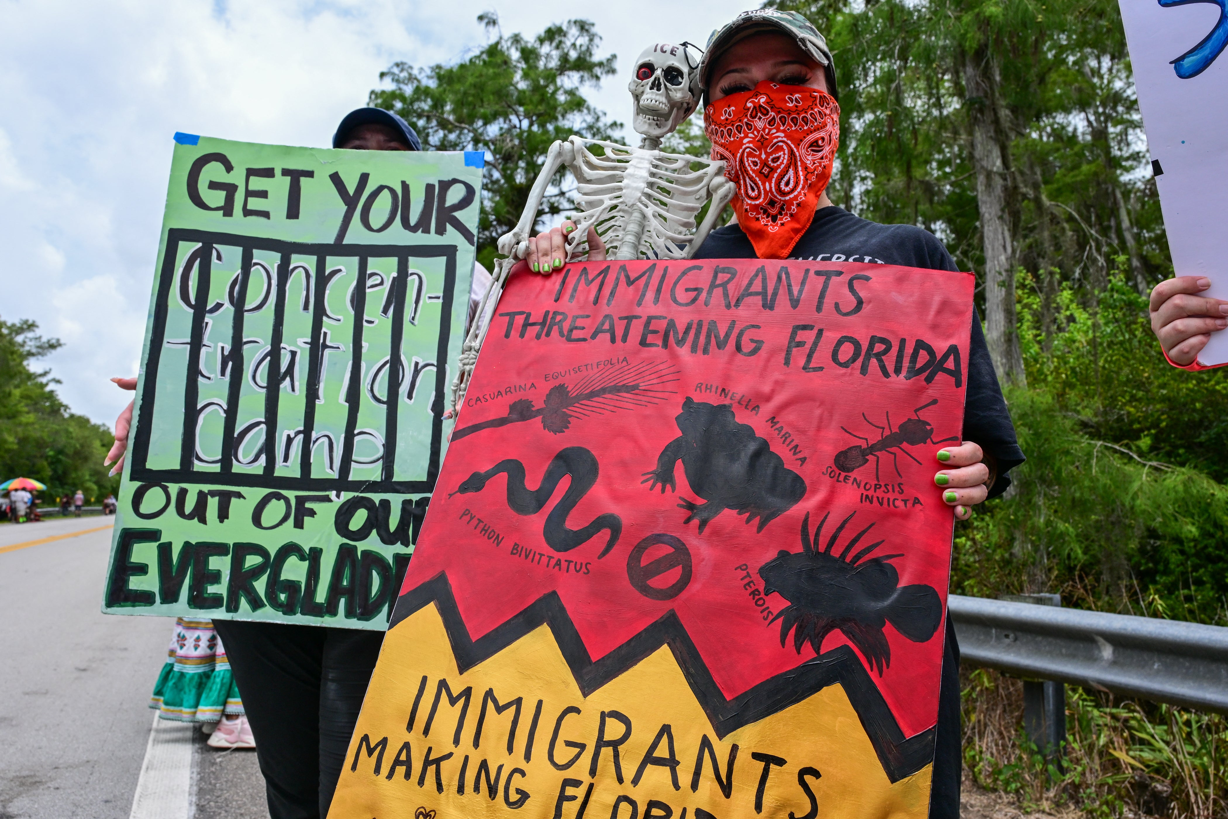 Demonstrators hold signs as they protest the construction of an immigrant detention center nicknamed “Alligator Alcatraz” in the heart of Florida’s Everglades