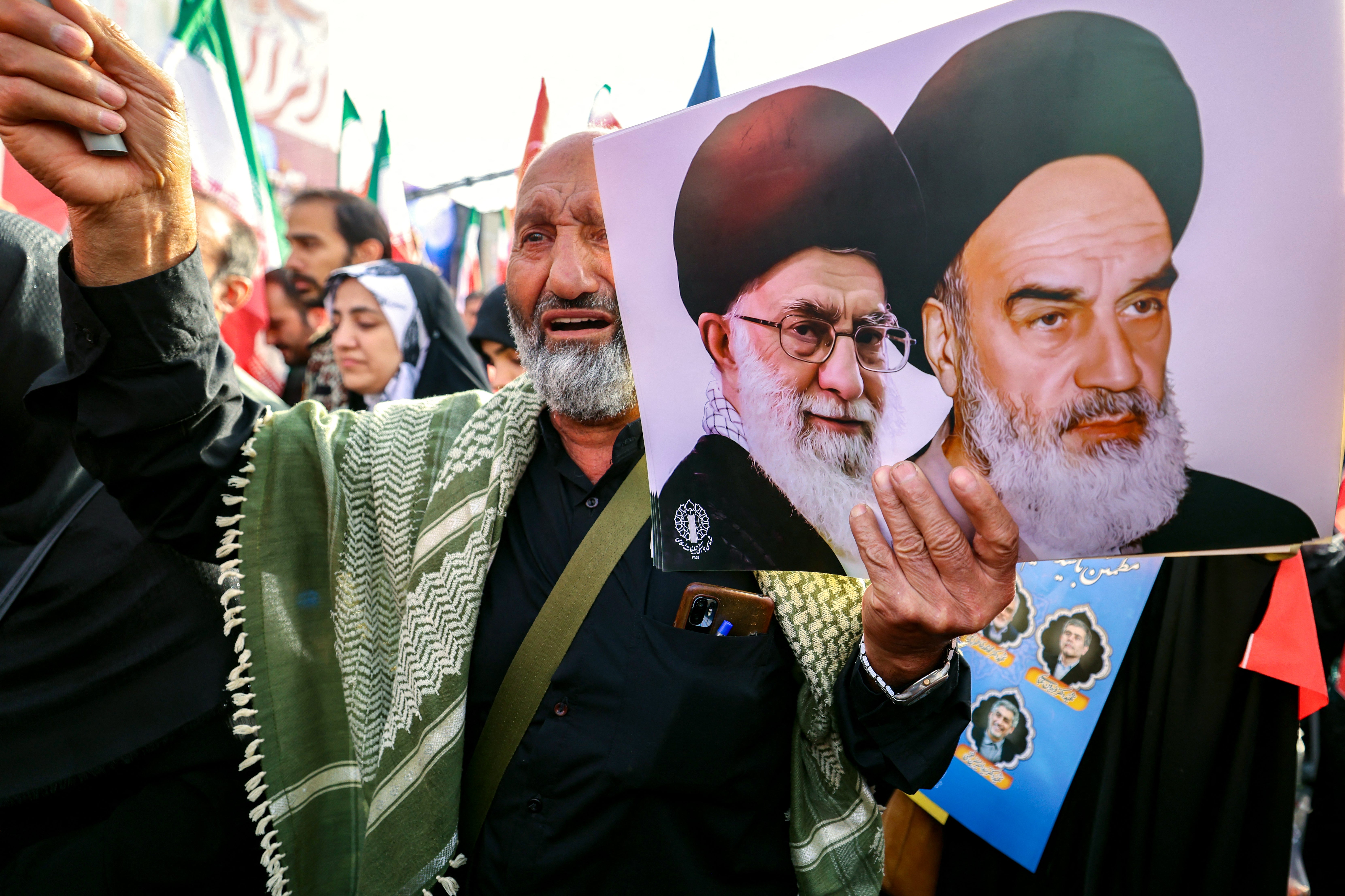 A man holds portraits of Iran's supreme leader Ayatollah Ali Khamenei and the late supreme leader Ayatollah Ruhollah Khomeini