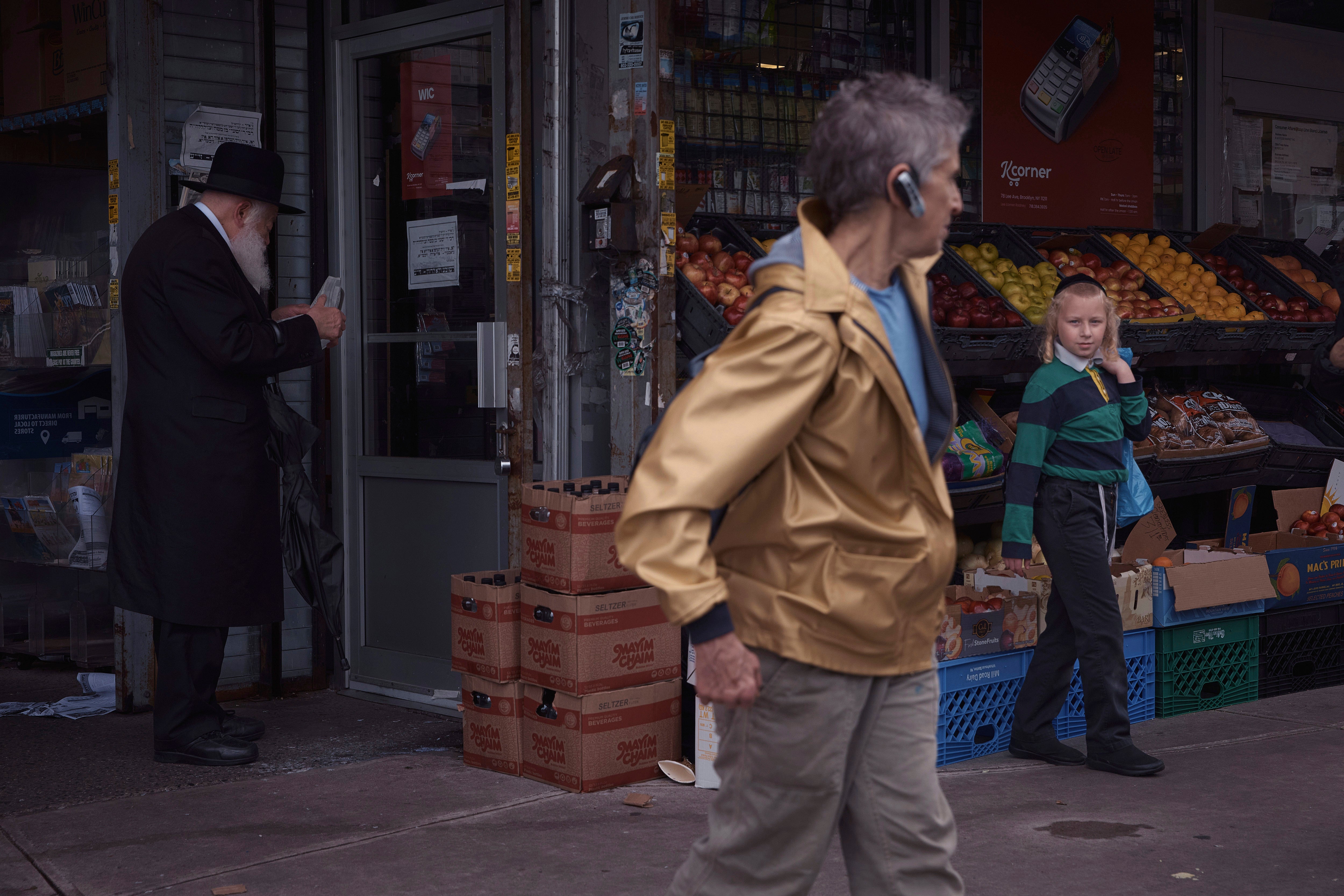 A tourist passes ultra-Orthodox Jews during a guided walk through the Hasidic section of Williamsburg in the Brooklyn borough of New York on Monday, June 16, 2025