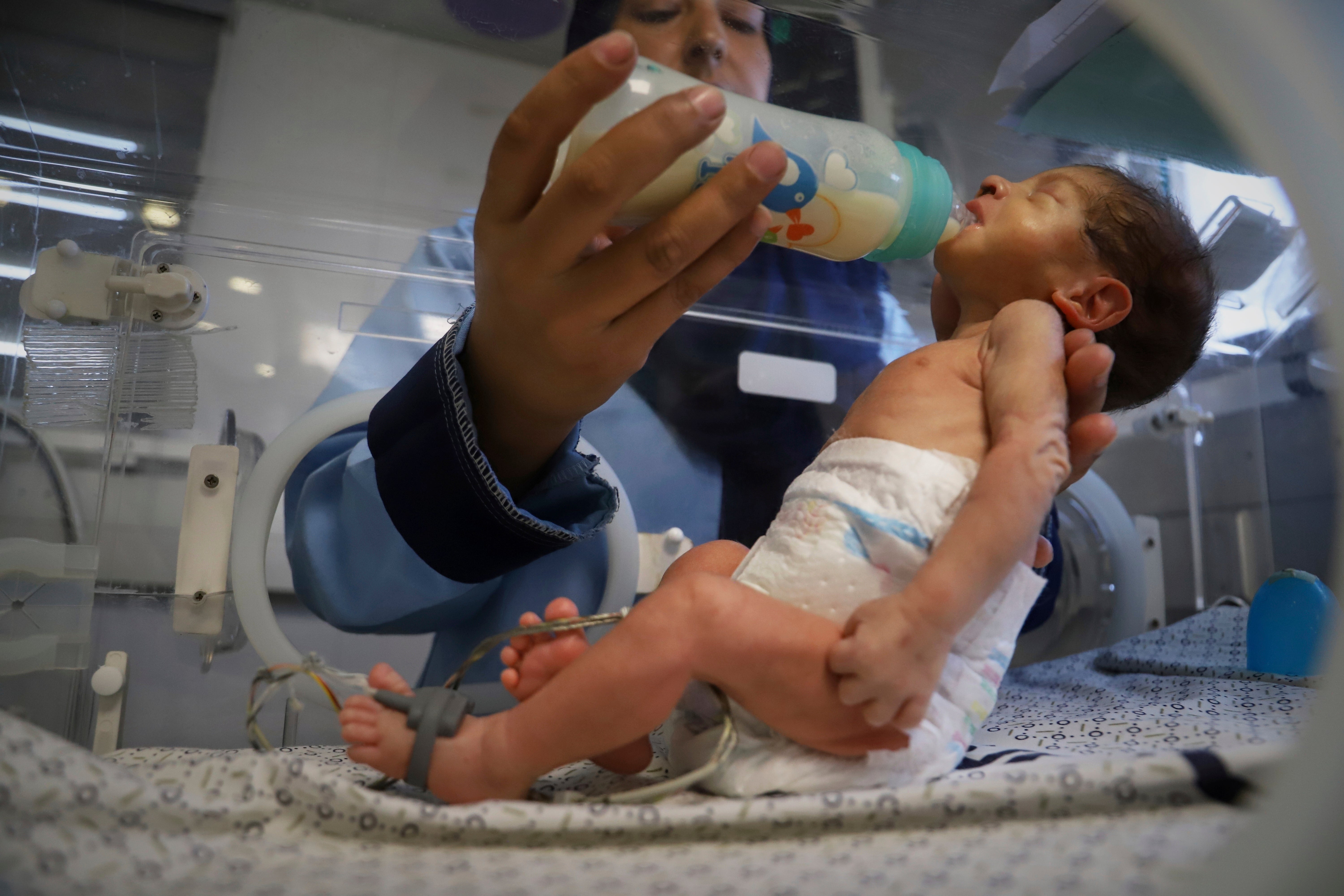 A nurse feeds a prematurely born baby lying in an incubator at the neonatal intensive care unit of Nasser Hospital in Khan Younis, southern Gaza Strip, Thursday, 19 June 2025