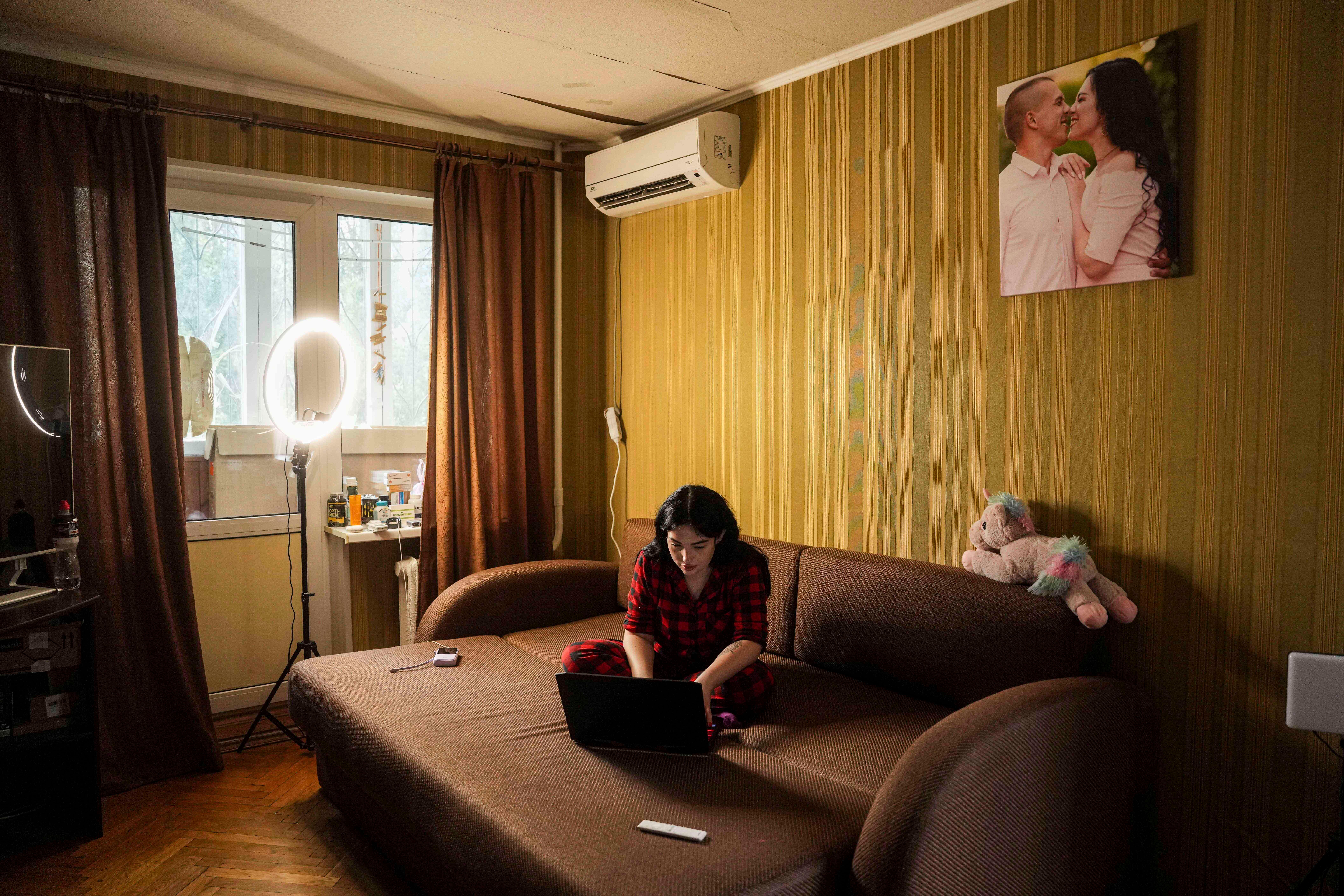 Olha Kurtmalaieva works on a laptop in her apartment