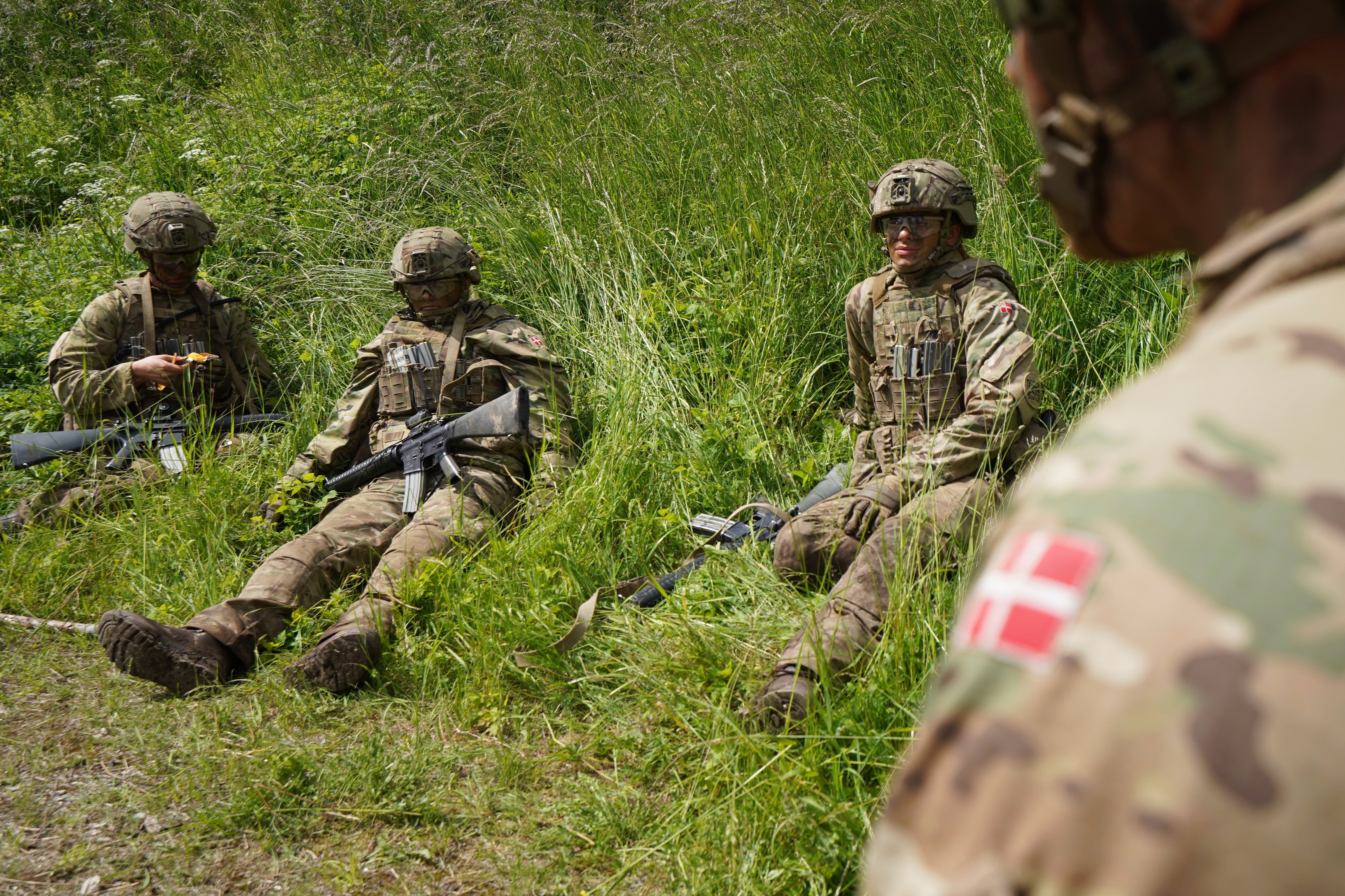 Young conscripts sit waiting in the grass during final exercises at a training area close to Royal Danish Army’s barracks in Hovelte, 25 kilometres north of Copenhagen, Denmark, Wednesday, June 11, 2025