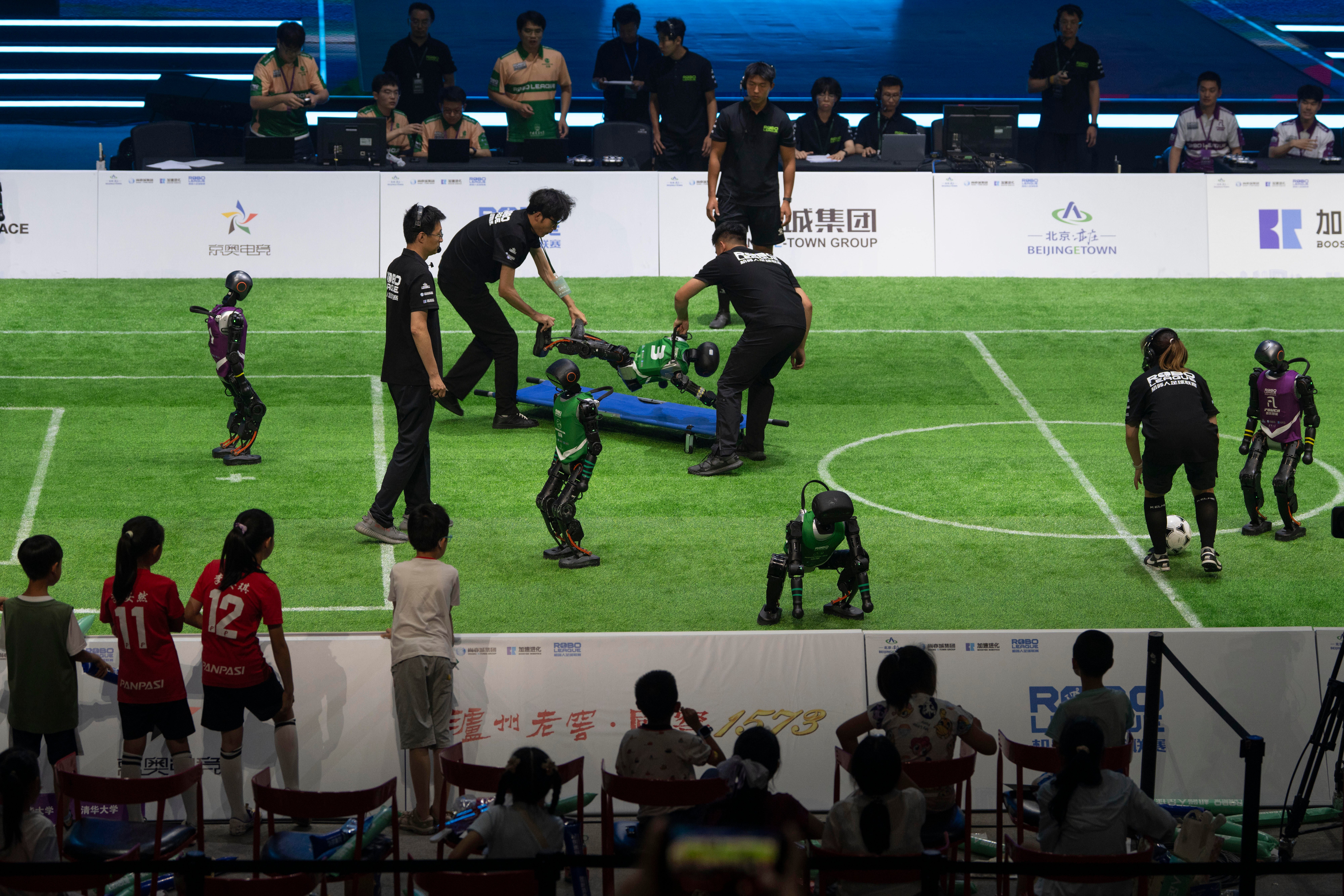 A robot is carried off the field during a game between AI-powered humanoids (AP Photo/Ng Han Guan)