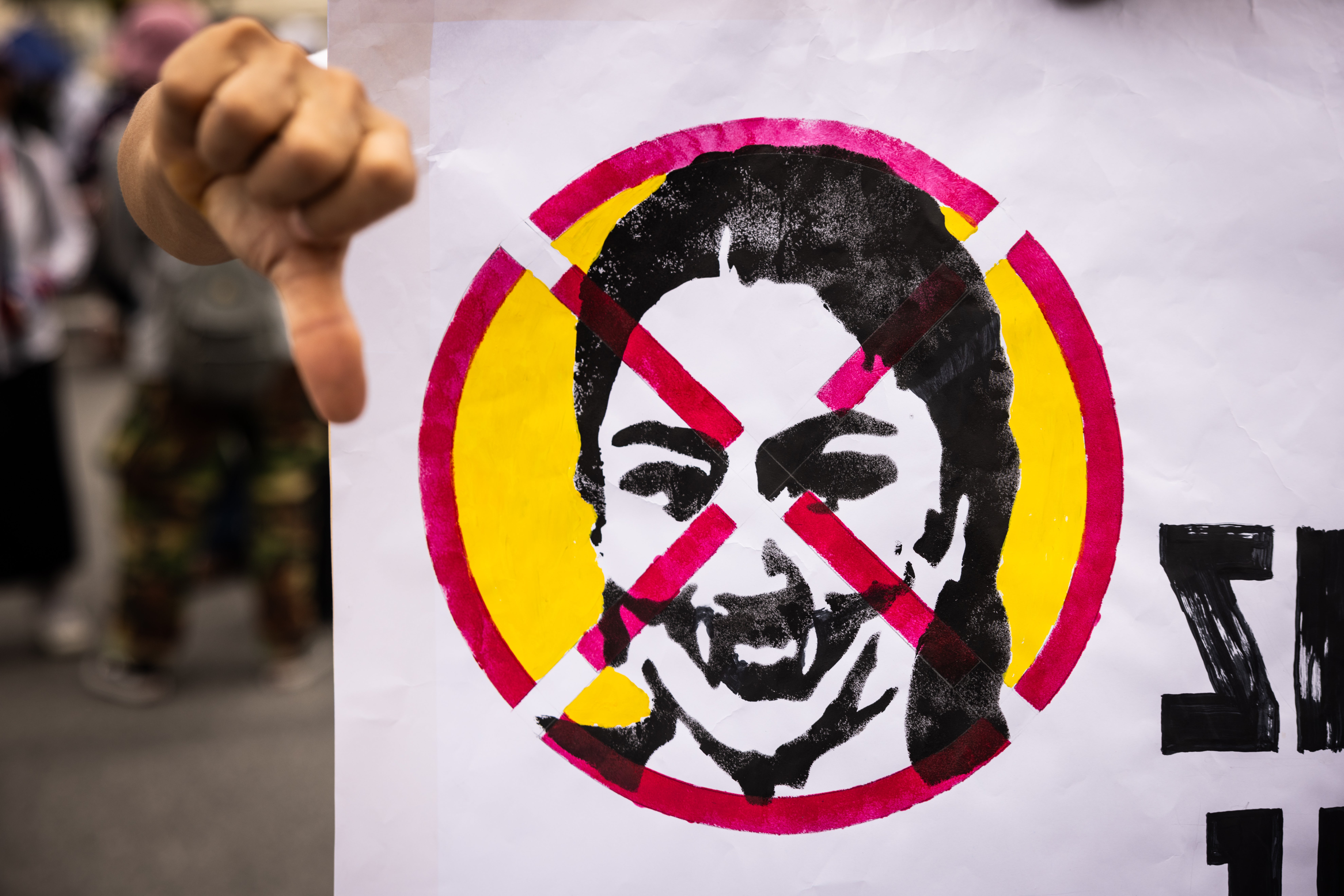 Protesters hold a sign with a photo of prime minister Paetongtarn Shinawatra crossed out at Victory Monument in Bangkok, Thailand