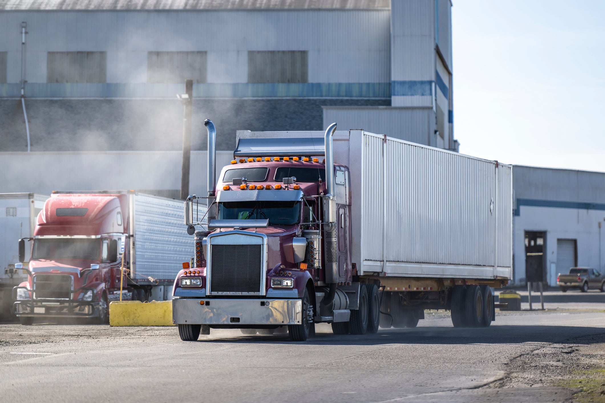A commerical big-rig leaves an industrial depot to make a delivery